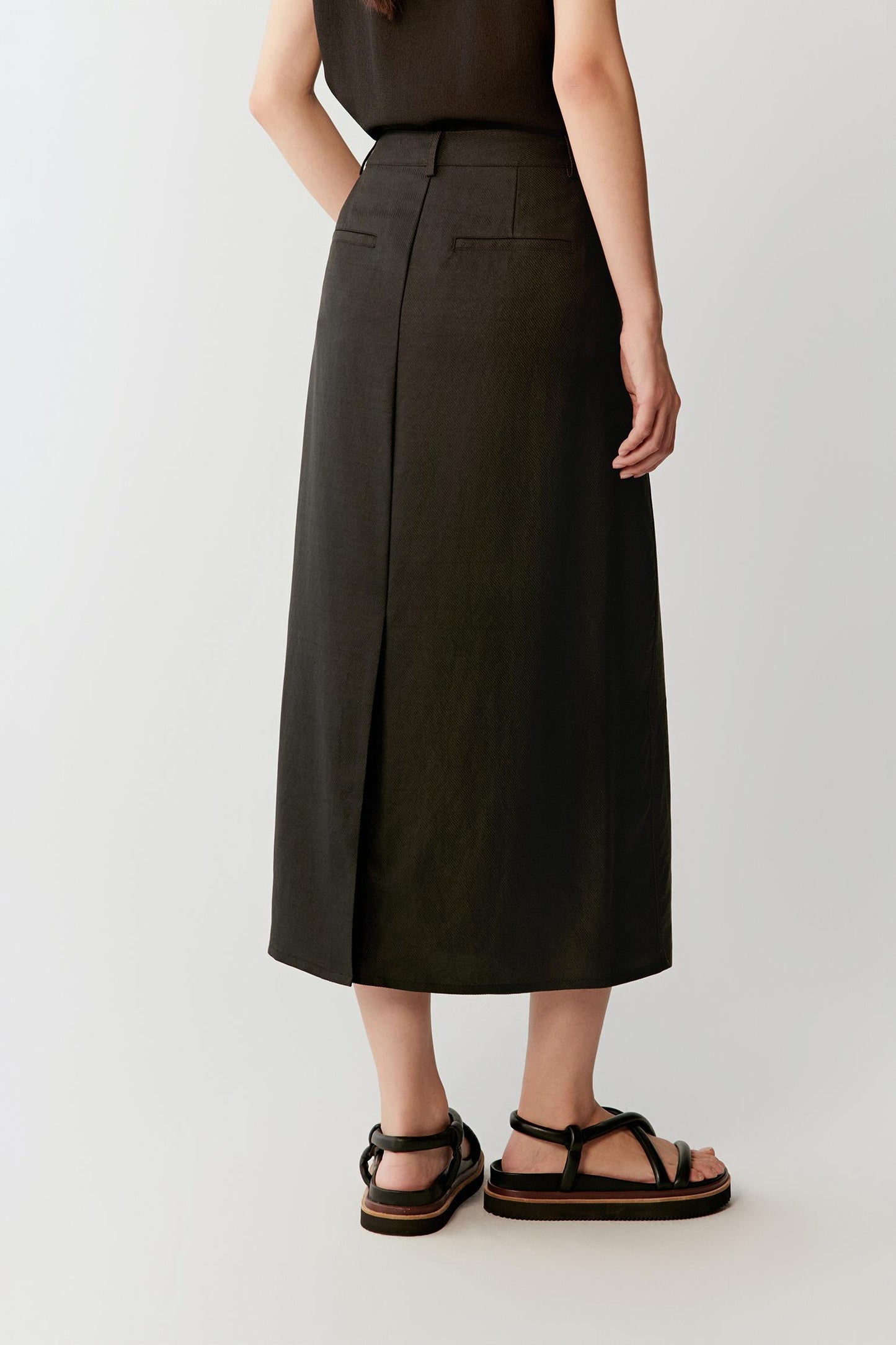 Full-length back view showing the central back vent and clean line of the skirt, highlighting the fluid drape and lightly textured matte surface