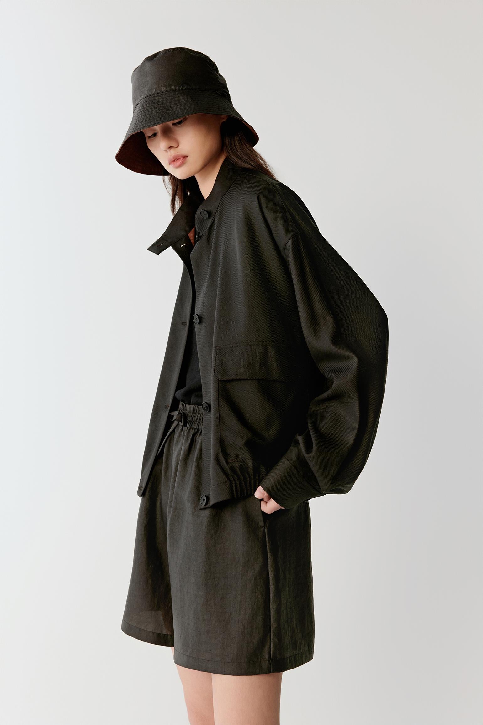 Focusing on the stand collar and upper front construction, detailing the compact woven texture, matte finish and subtle tonal variation within the black fabric surface