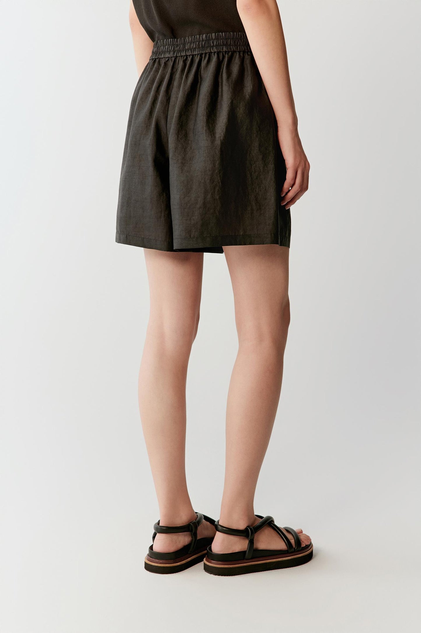 Side or back view highlighting the fluid cut and lightly textured woven surface of the shorts