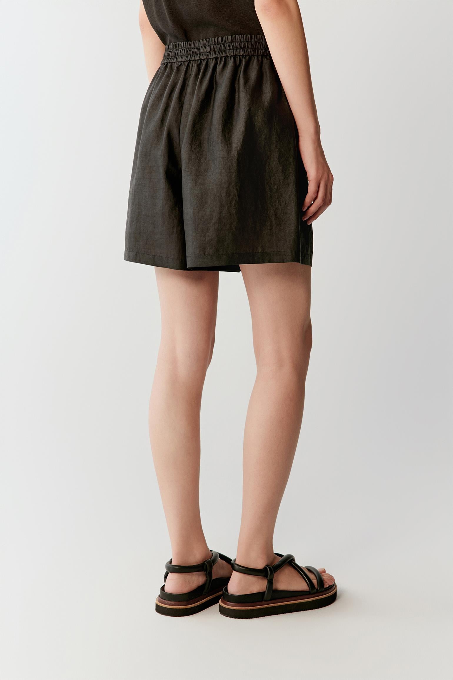 Side or back view highlighting the fluid cut and lightly textured woven surface of the shorts