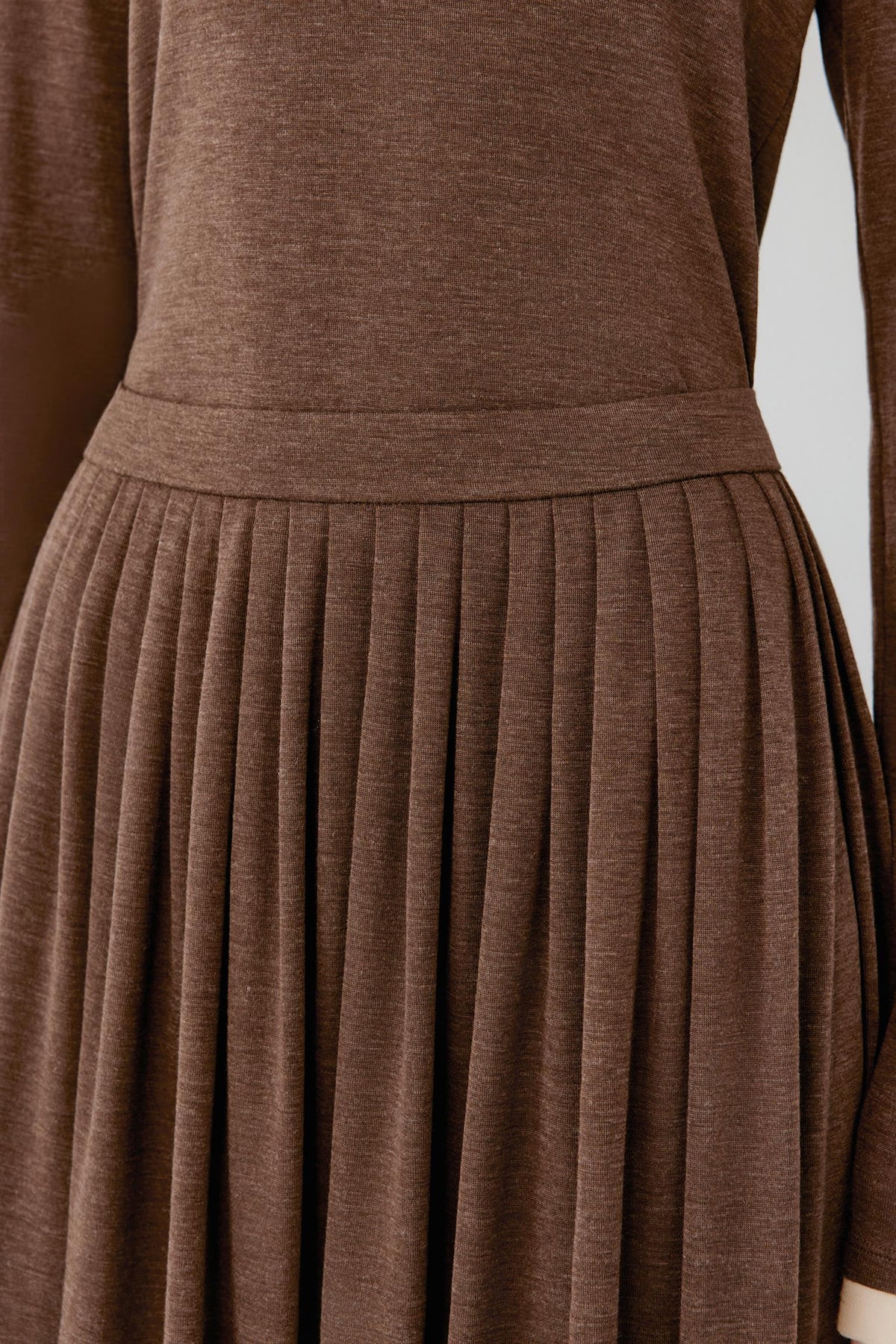 Close-up of a brown long-sleeve top and matching pleated skirt set, showing the waistband and fabric texture.