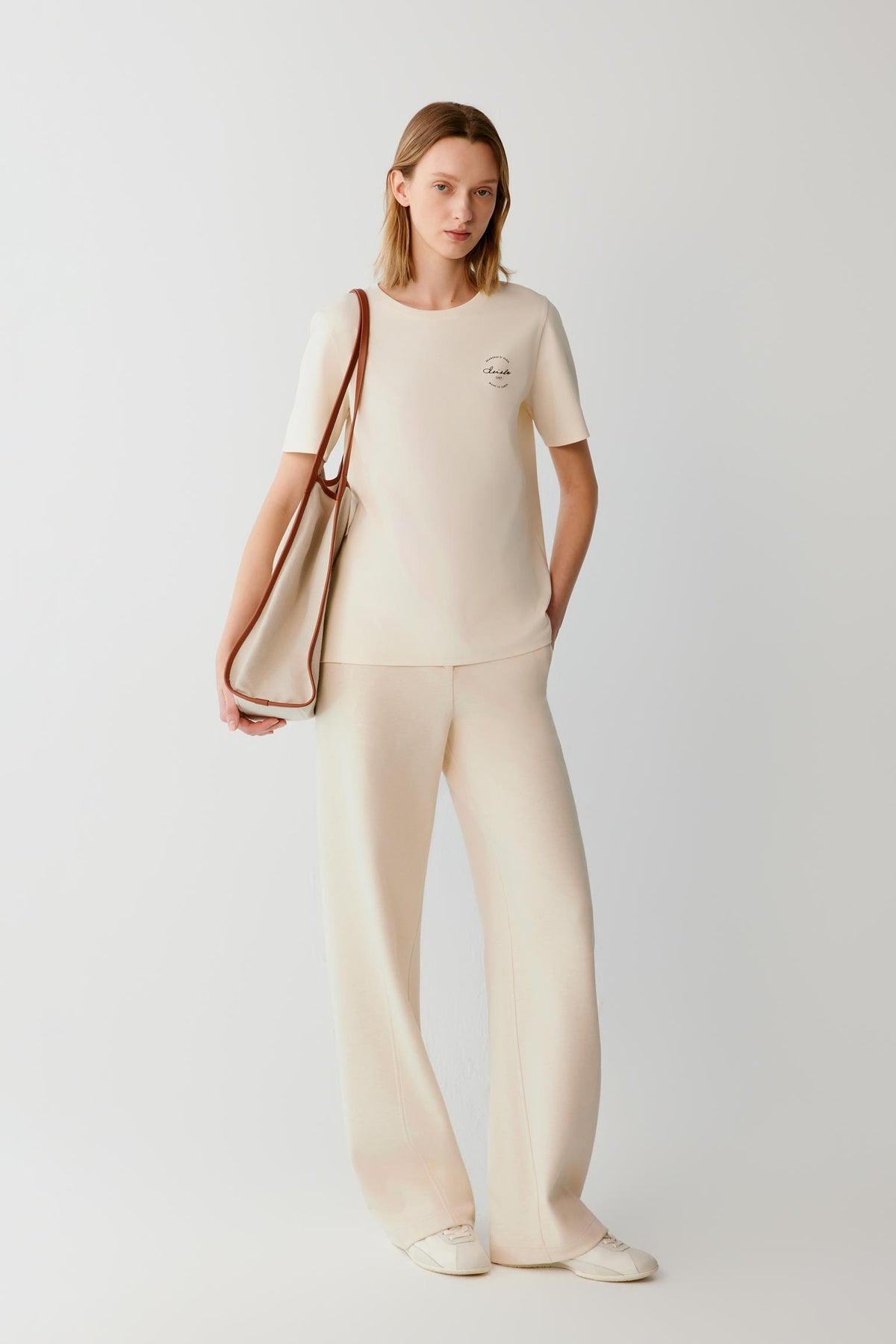 Front view of a woman wearing beige cotton and yak trousers, showing the wide-leg silhouette and high waist.
