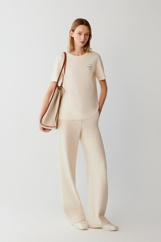 Front view of a woman wearing beige cotton and yak trousers, showing the wide-leg silhouette and high waist.