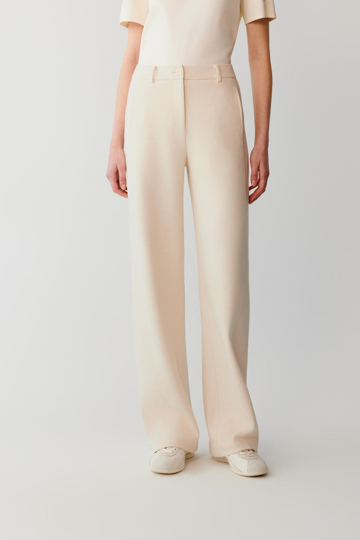 Front view of the beige cotton and yak trousers, highlighting the wide-leg cut and clean waistband.