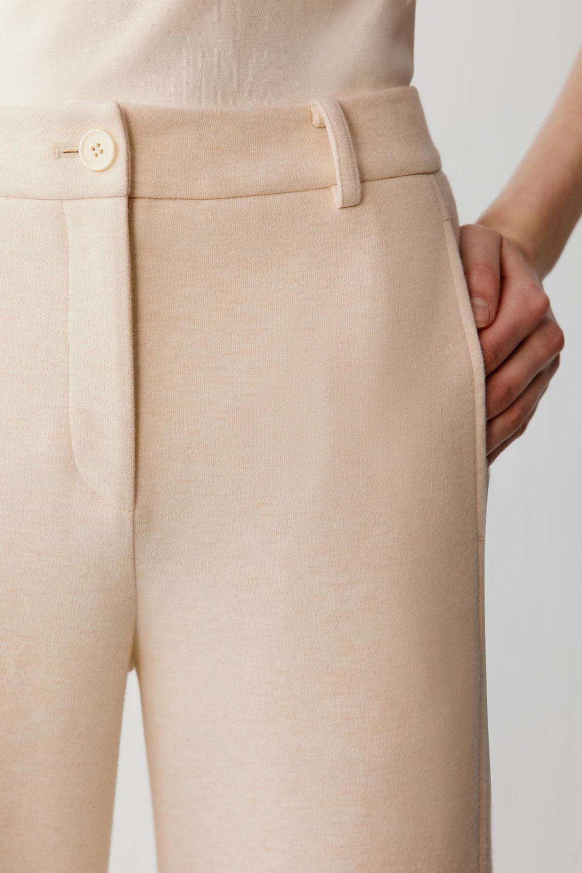 Close-up highlighting the waistband, belt loops and front pocket of the beige cotton and yak trousers.