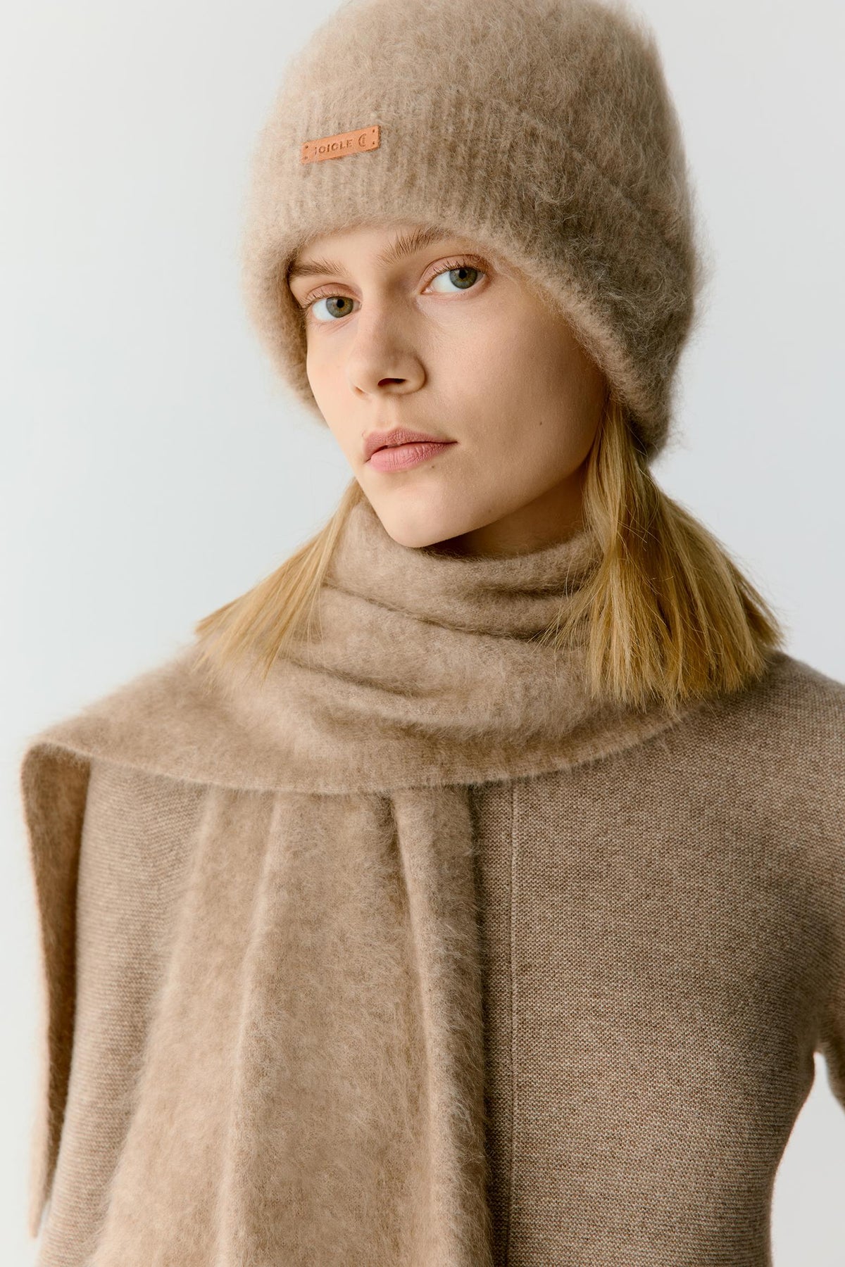 Front view showing the scarf layered over a matching taupe outfit. The generous dimensions allow the fabric to fall naturally through the body, demonstrating its lightweight structure, soft hand and enveloping silhouette.