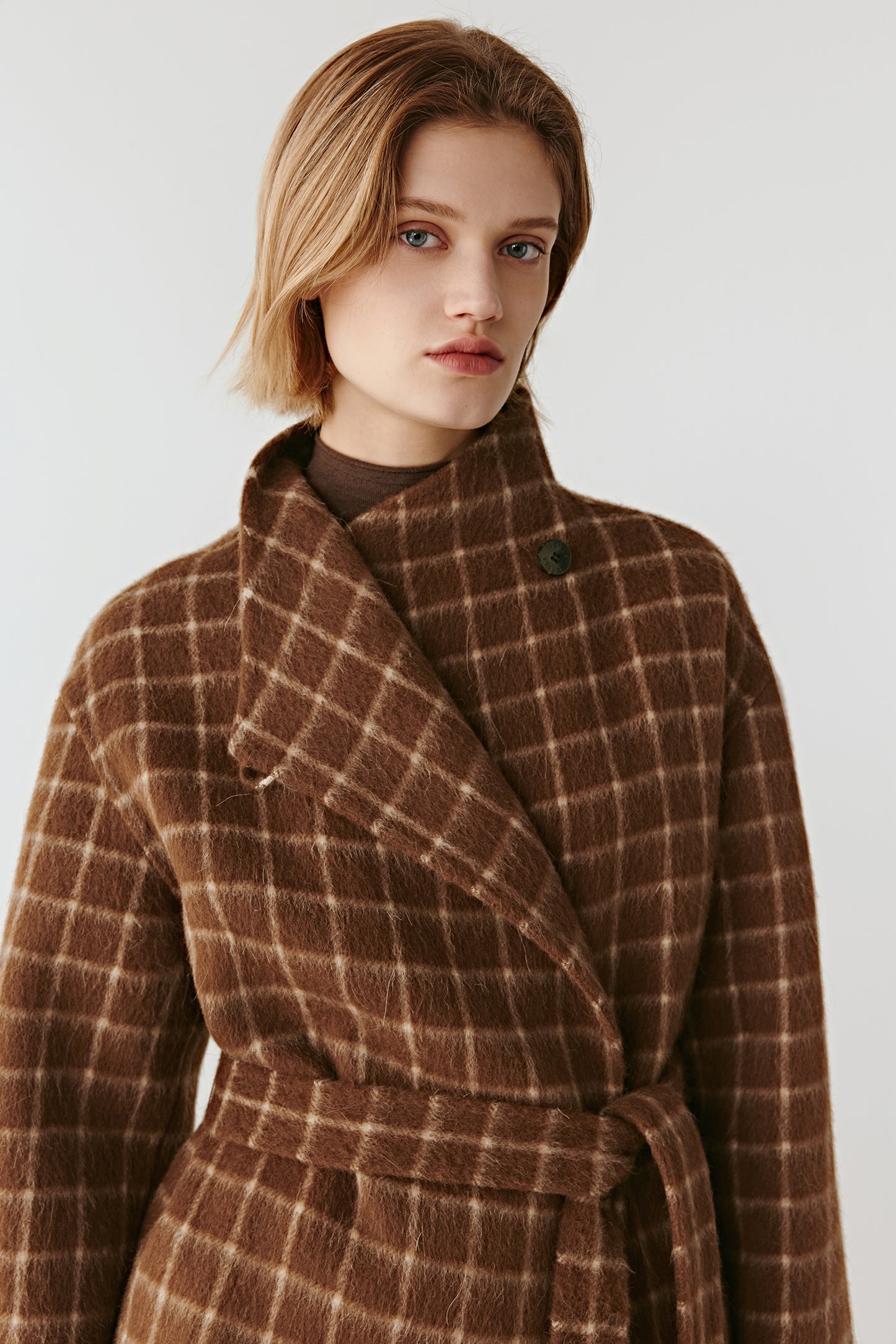 Close-up of the checked wool coat’s neckline and fabric, revealing the subtle check motif and soft brushed texture.