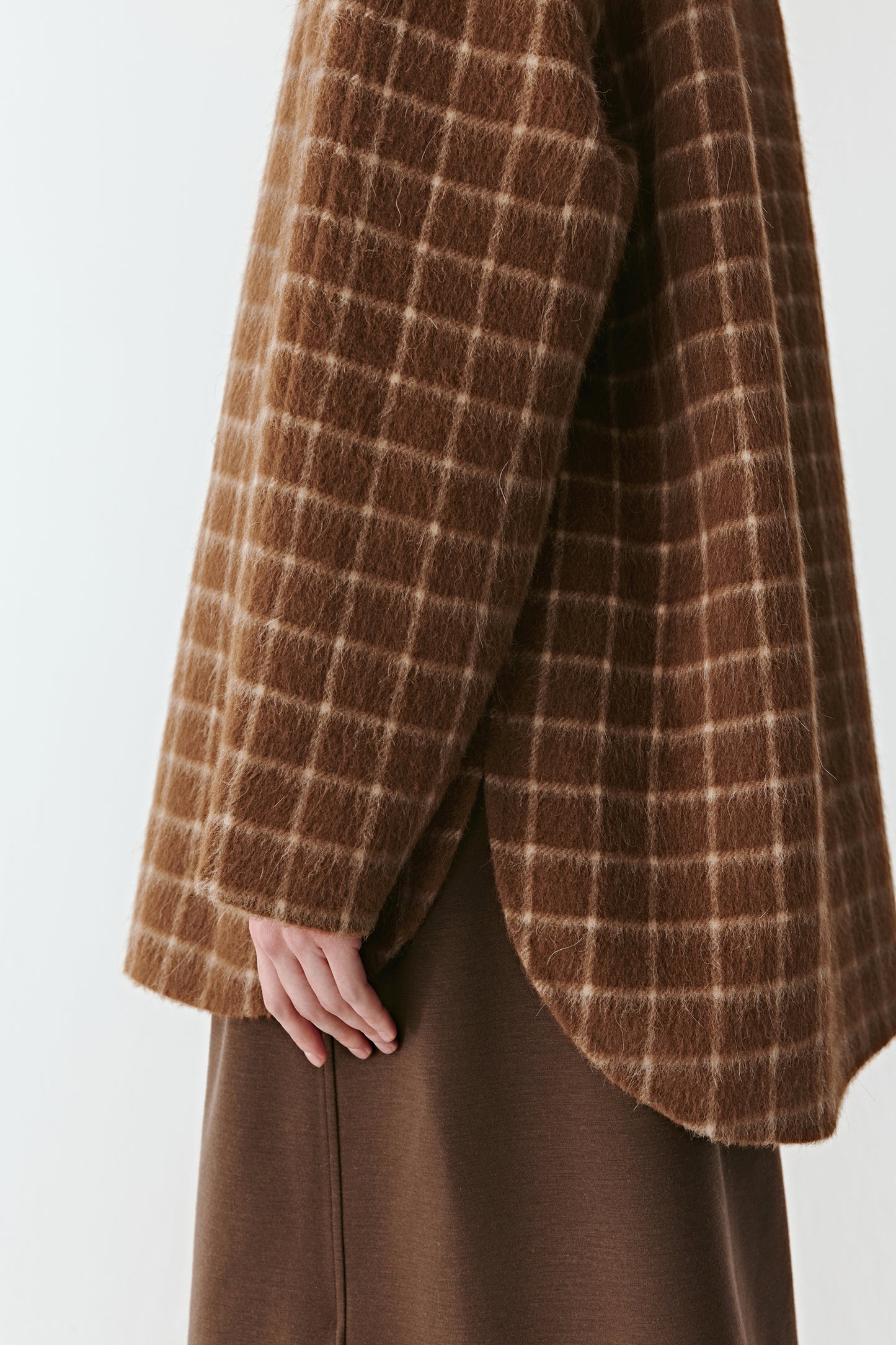 Detail close-up of the sleeve and check pattern of the double-faced wool coat, highlighting texture and weave.