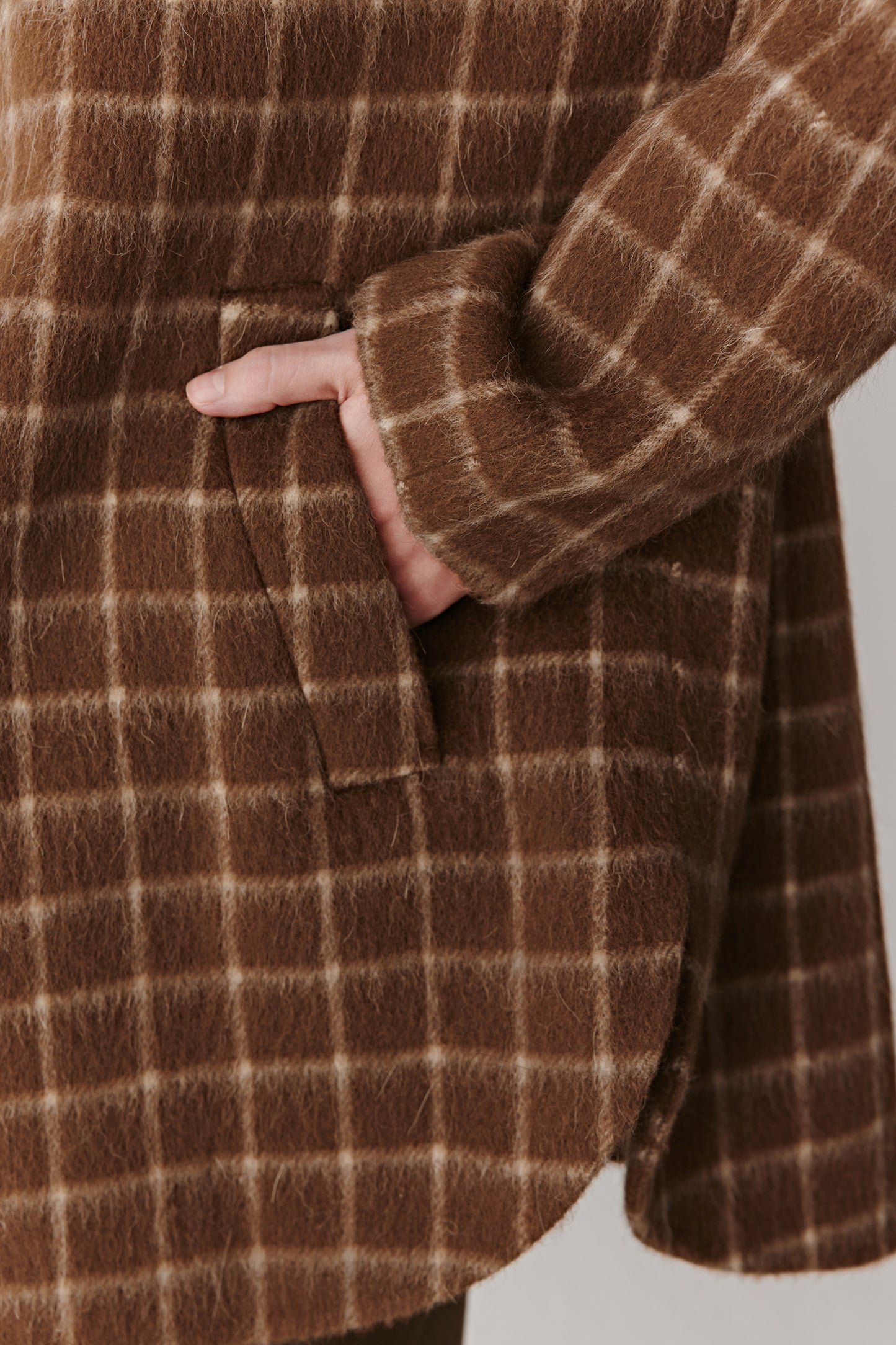 Detail close-up of the sleeve and check pattern of the double-faced wool coat, highlighting texture and weave.