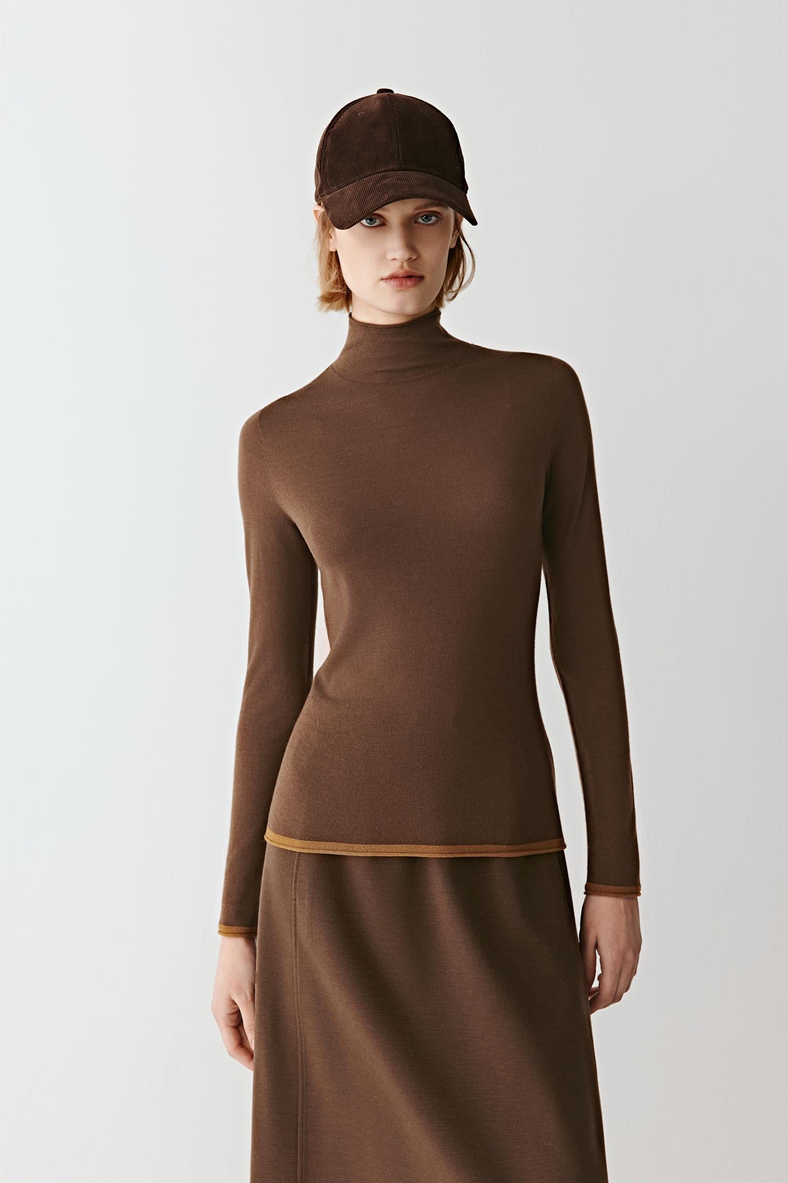 Three-quarter view highlighting the fitted silhouette, long sleeves, and warm merino wool texture.