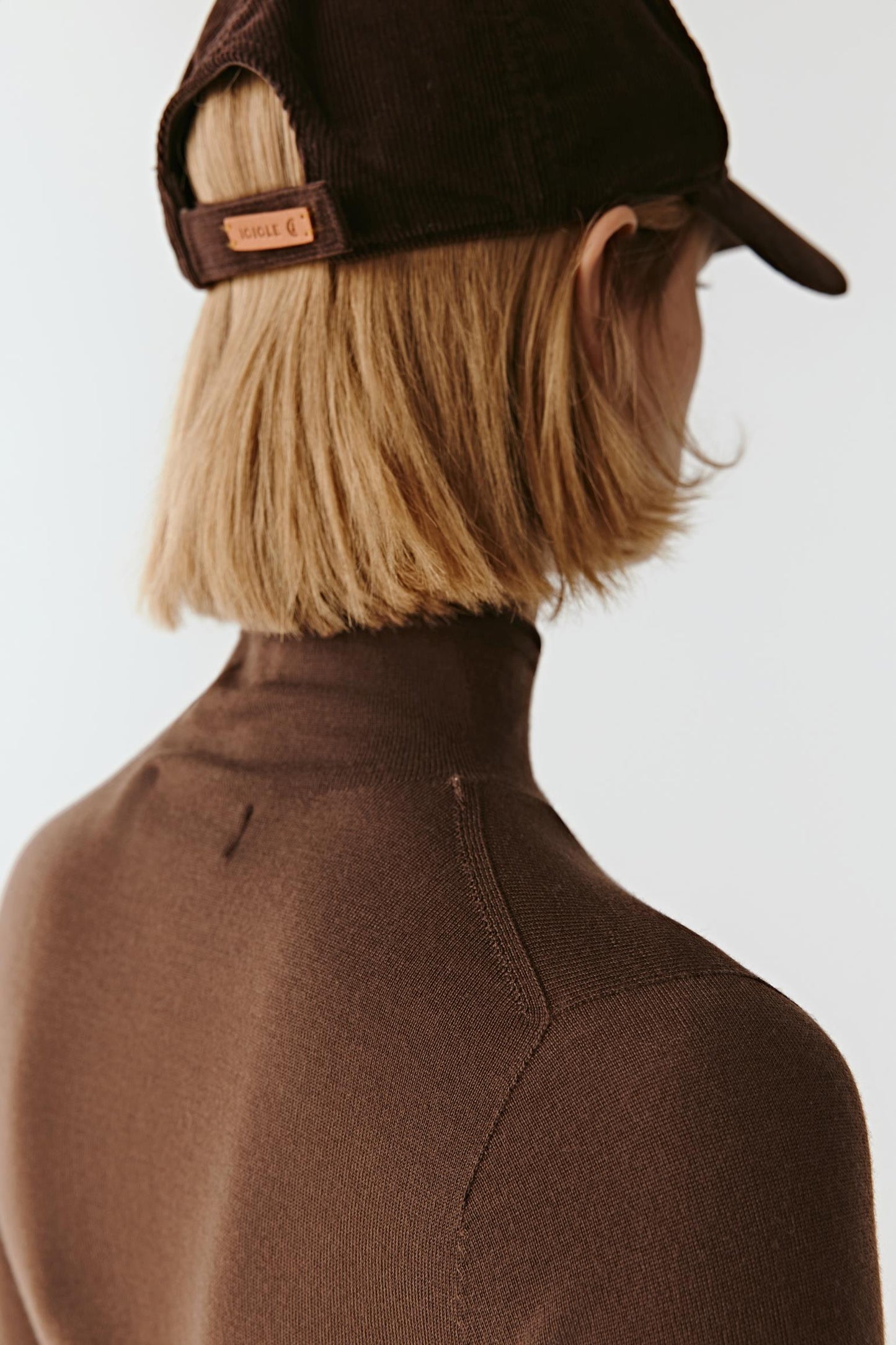 Detail close-up of the upper back of the merino wool mock-neck pullover, showing the precise knit structure.