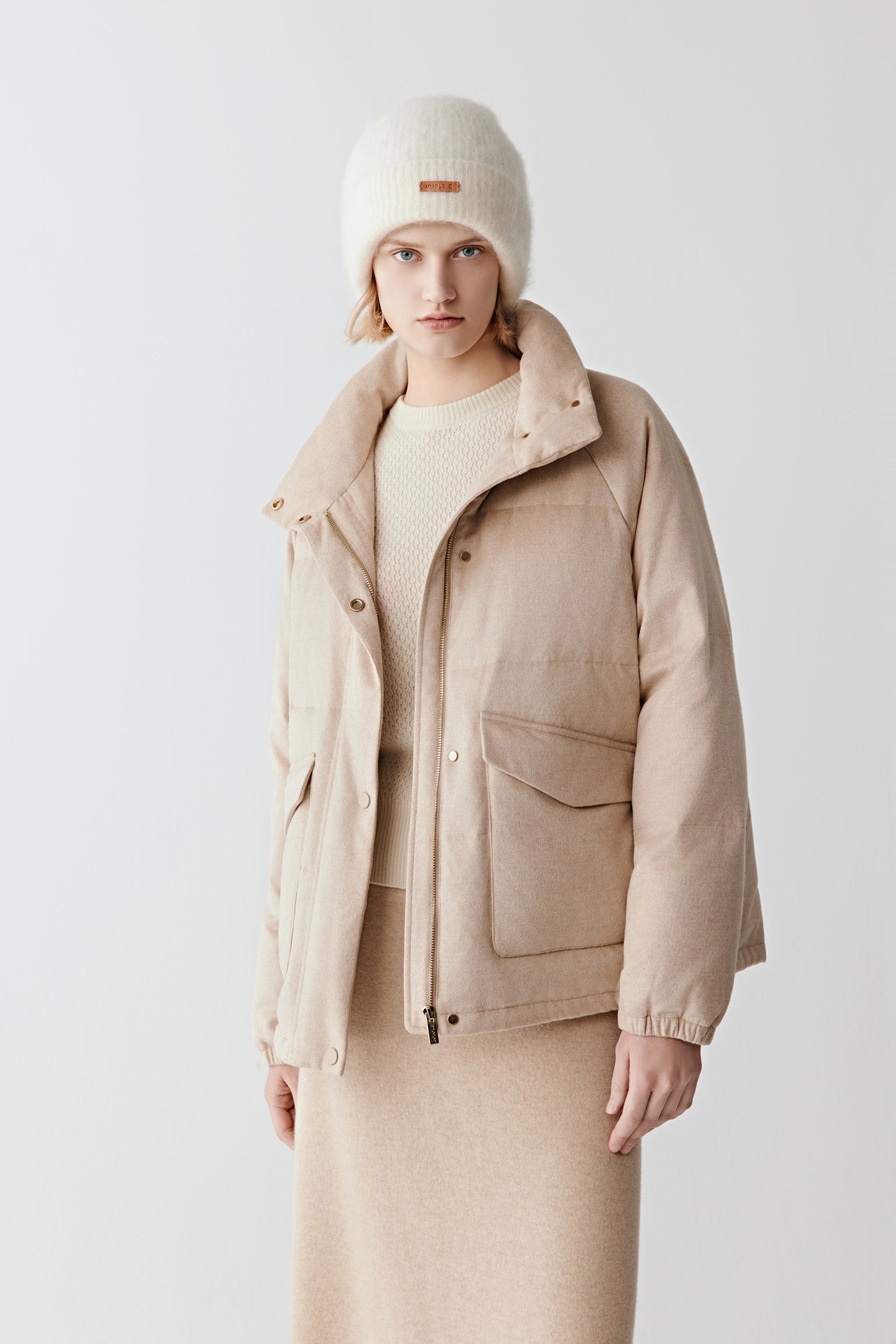 Three-quarter view of the camel silk tweed down coat, highlighting the flap pockets, streamlined cut, and soft natural shade.