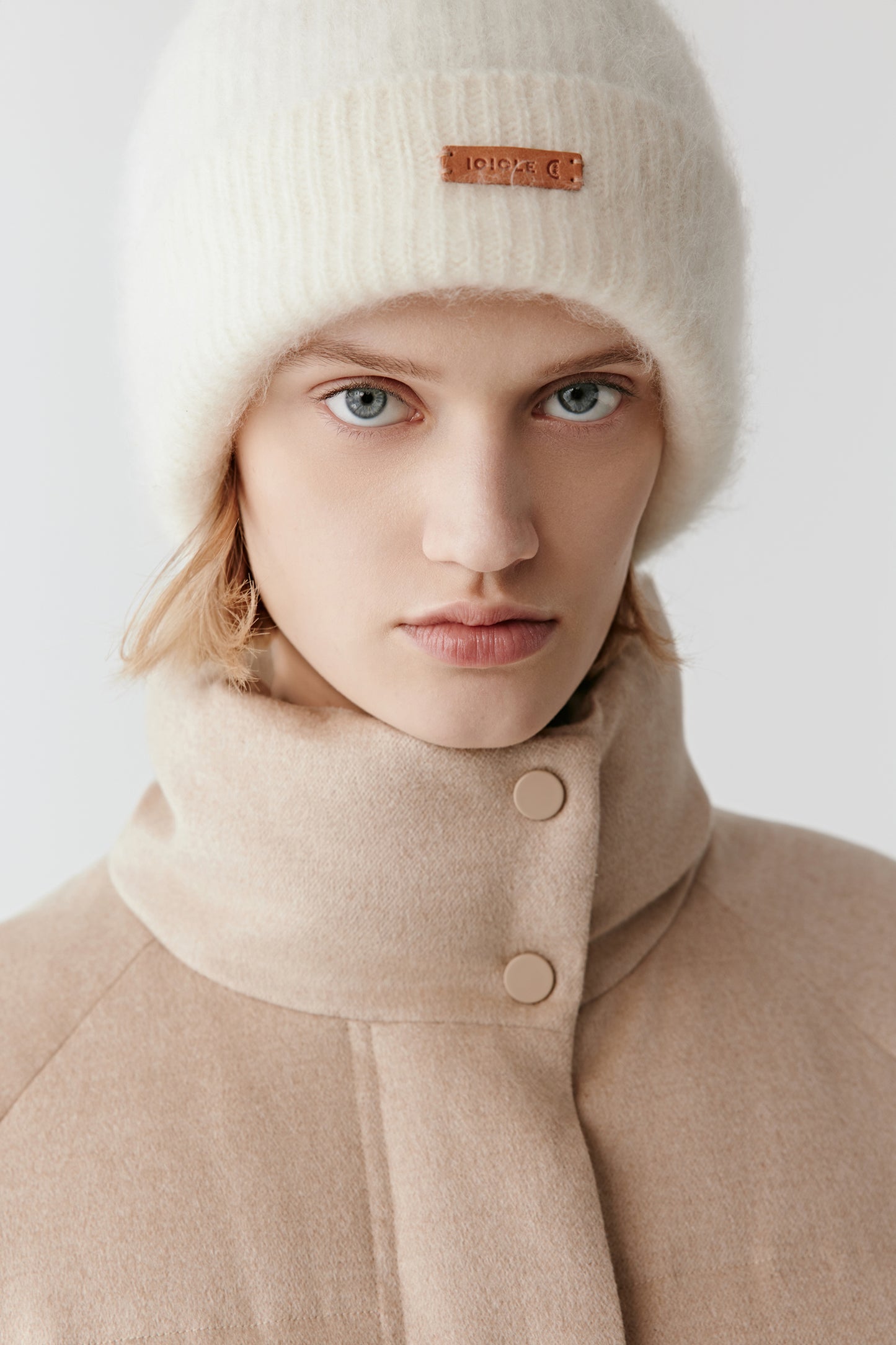 Close-up of the camel silk tweed coat’s padded stand collar and fine tweed texture.