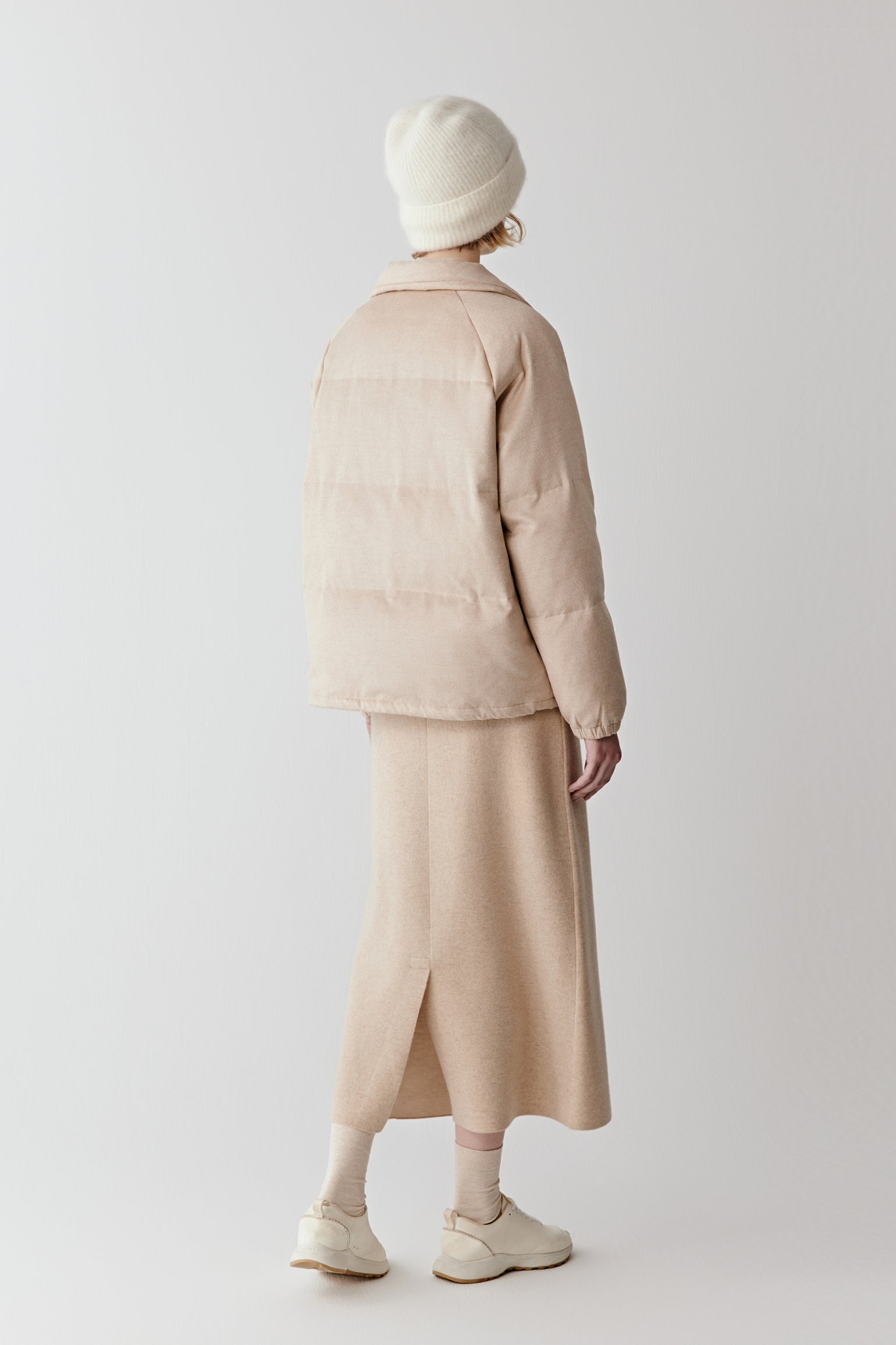 Side or back view of the long camel down coat, showing the straight silhouette and lightly padded structure.