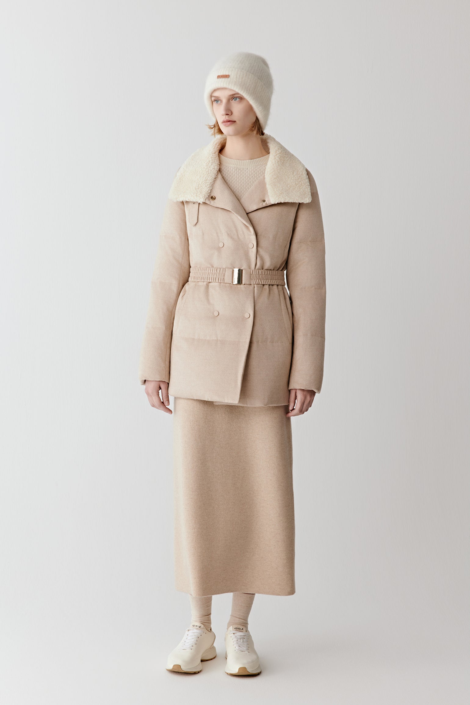 Full-length view of a light beige down coat in camel and silk tweed, featuring a high collar, belted waist, and clean, structured lines.