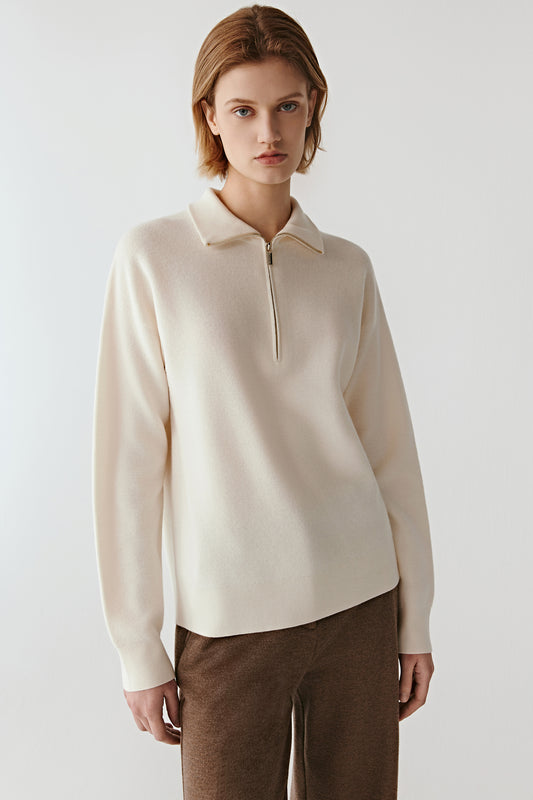 Front view of a cream worsted wool pullover with a zipped stand collar and clean, minimalist lines.