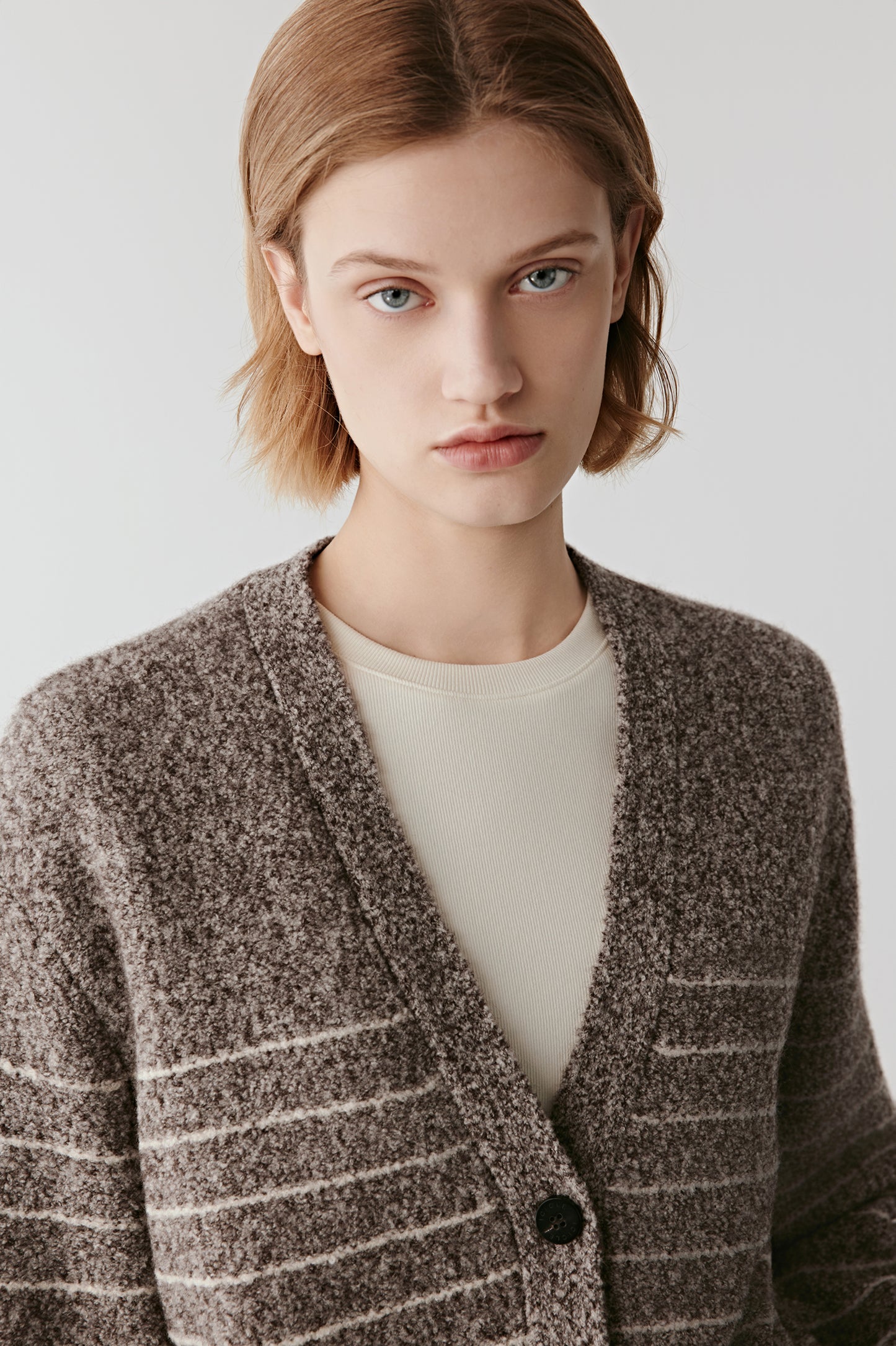 Close-up of the V neckline and button placket of the wool and yak cardigan, showing the natural melange stripes.
