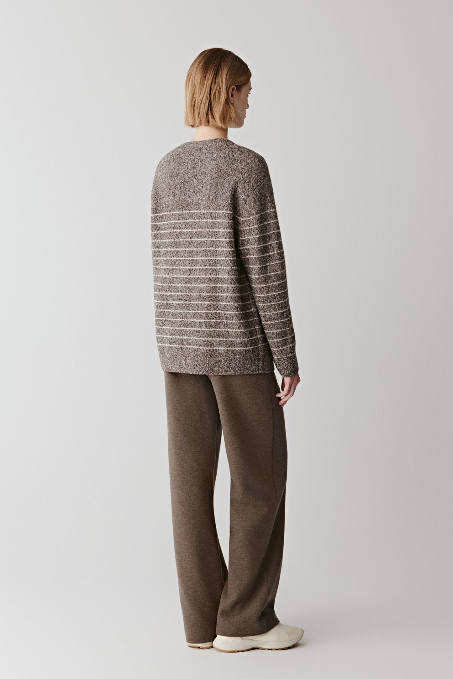 Back view of the striped cardigan, highlighting the clean lines and soft looped yarn texture.