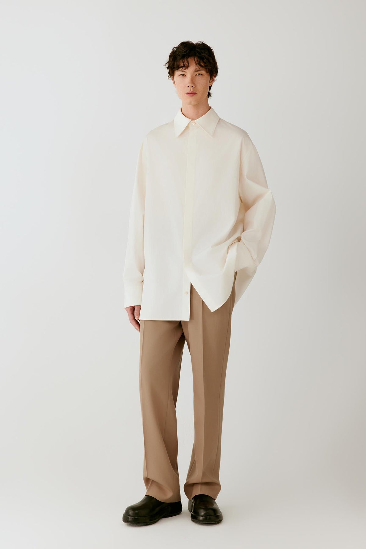 Full-length front view of a man wearing camel wool twill trousers, highlighting the straight-leg silhouette and clean drape.