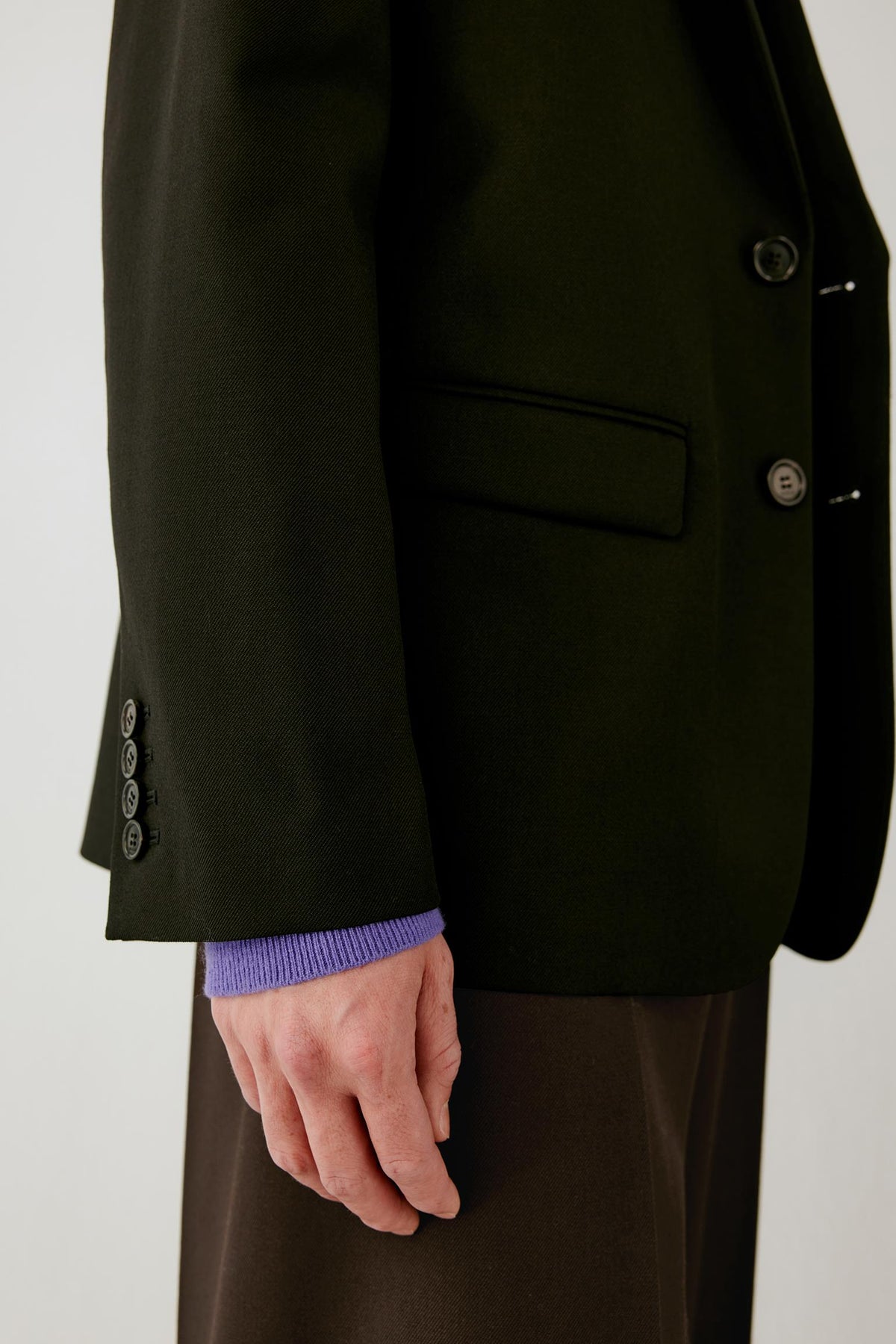 Close-up of the sleeve highlighting the buttoned cuff and smooth, structured wool twill fabric.