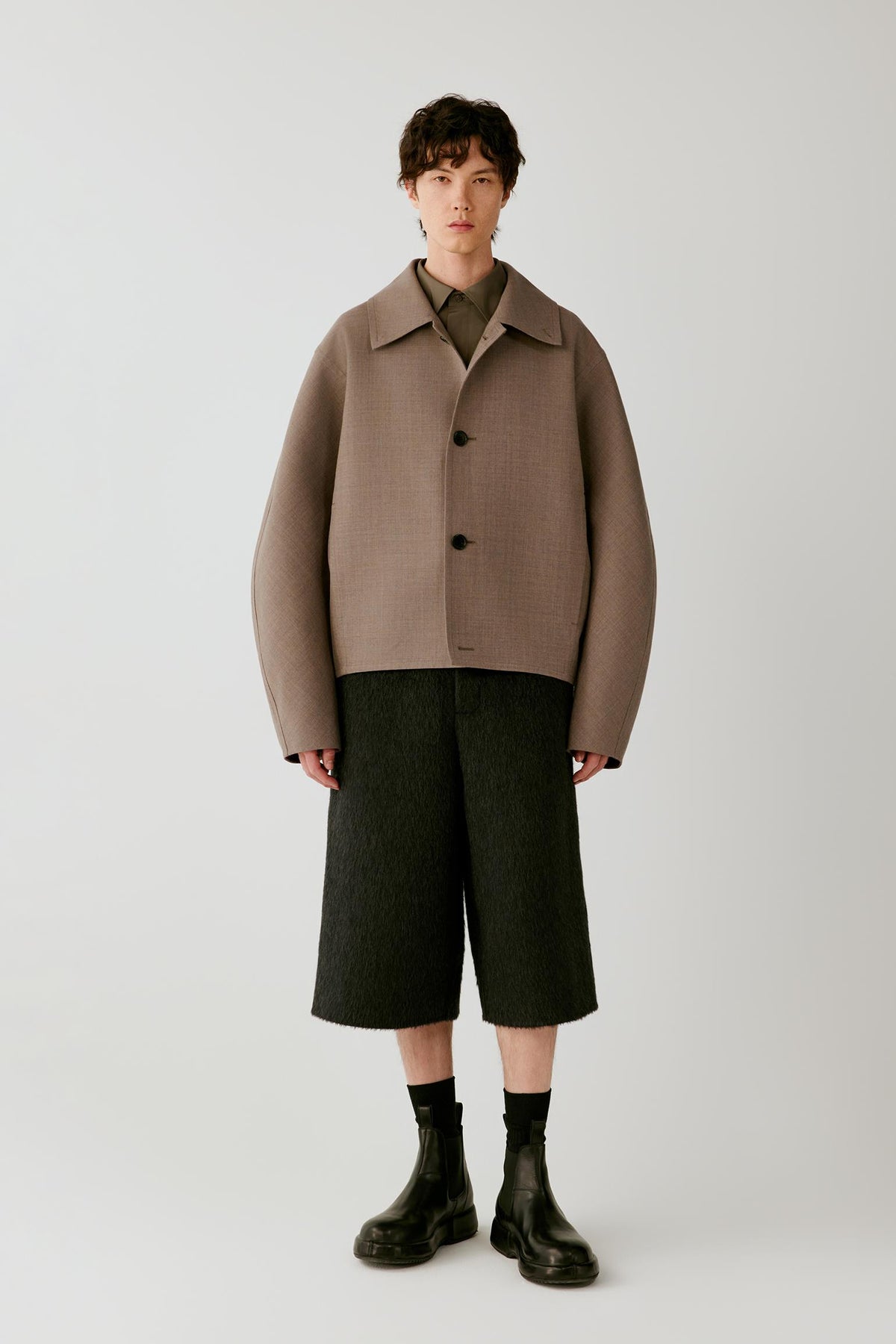 Full-length front view showing the jacket with black shorts, emphasizing the dropped shoulders and clean construction.