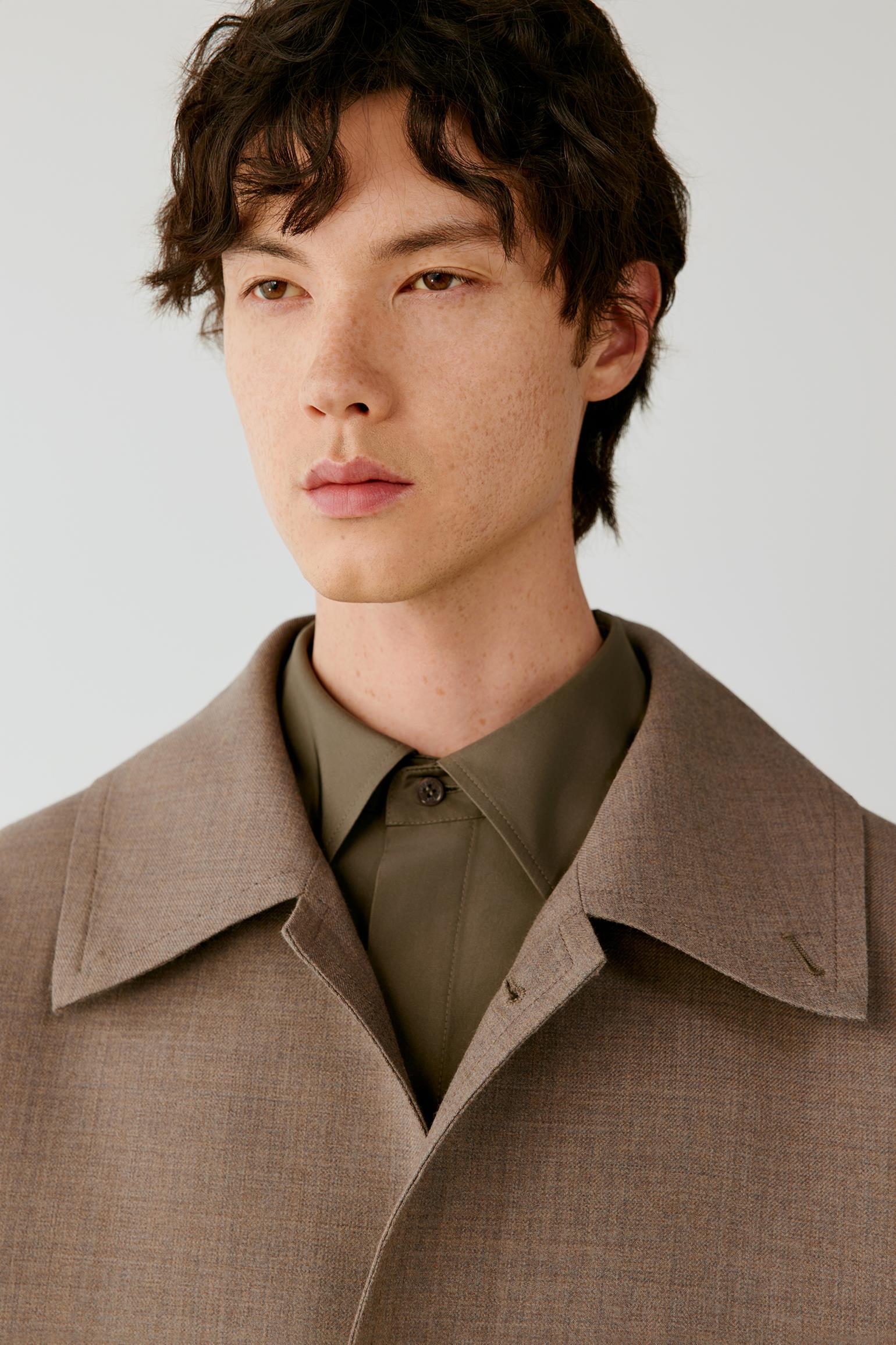 Close-up highlighting the pointed collar, top button and smooth double-face wool and silk surface.