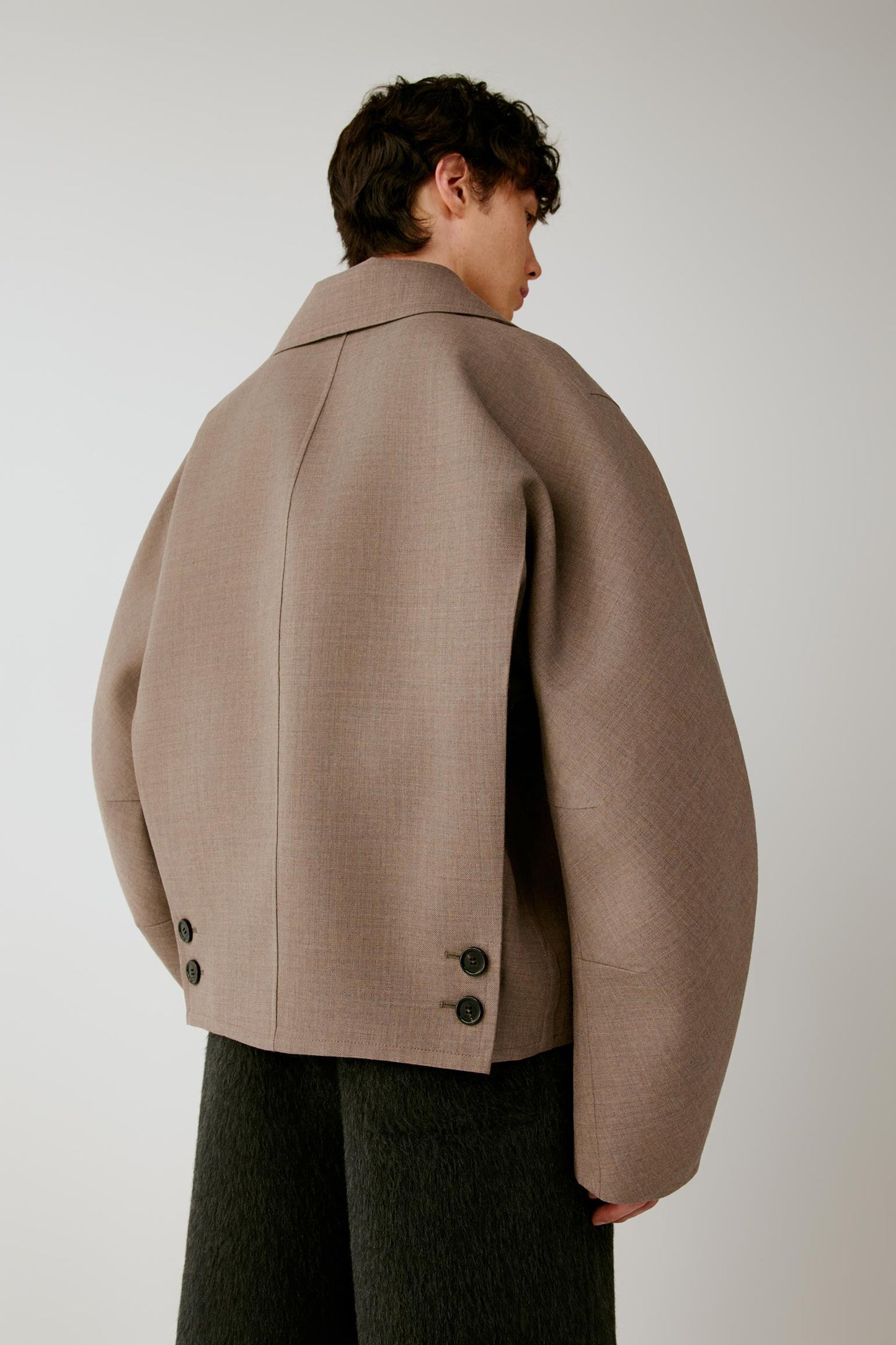 Three-quarter back view showing the clean back construction, dropped shoulders and taupe melange surface.