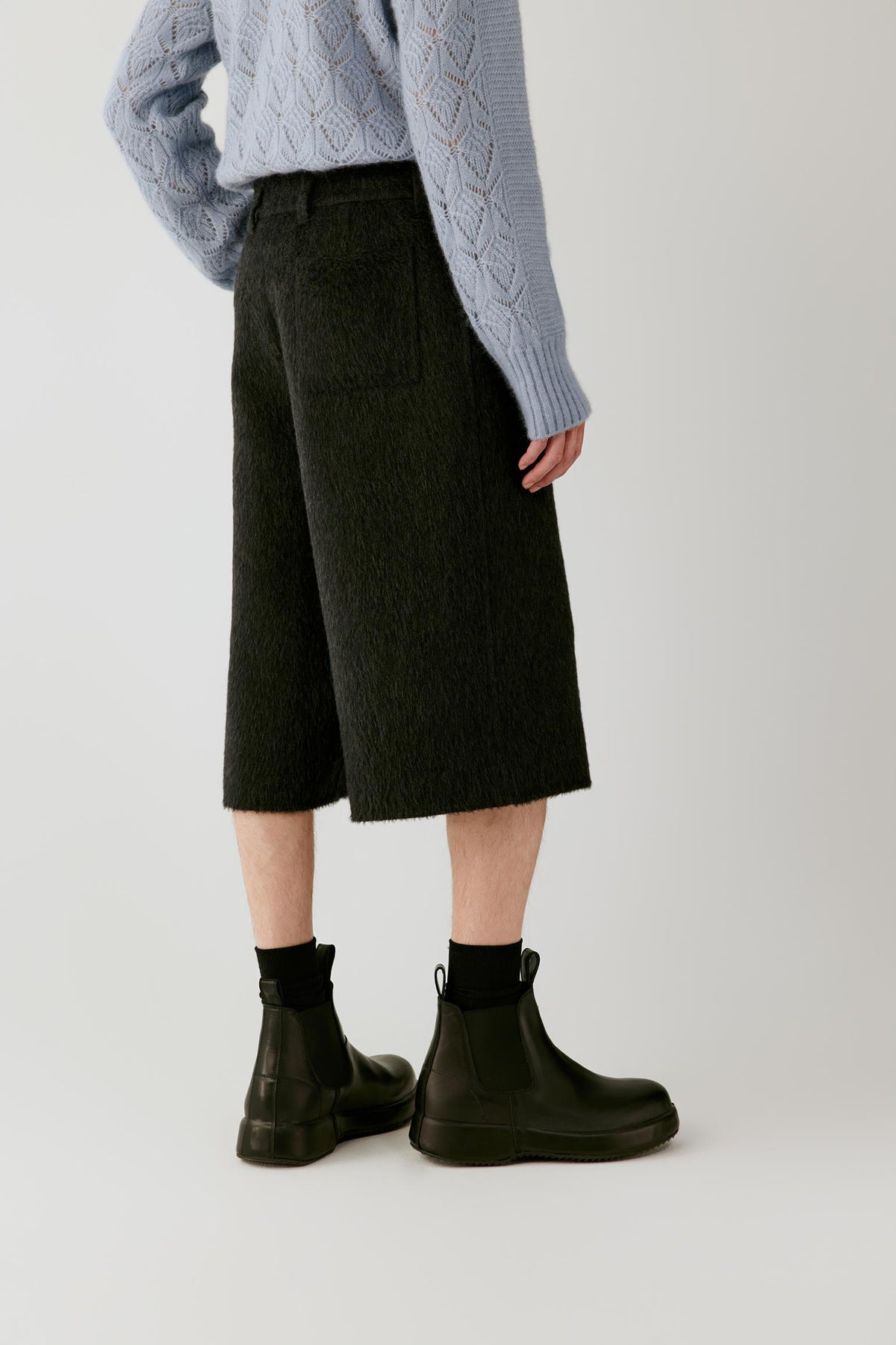 Three-quarter view highlighting the high-rise waist, wide cut and structured shape of the anthracite melange camel and mohair shorts.