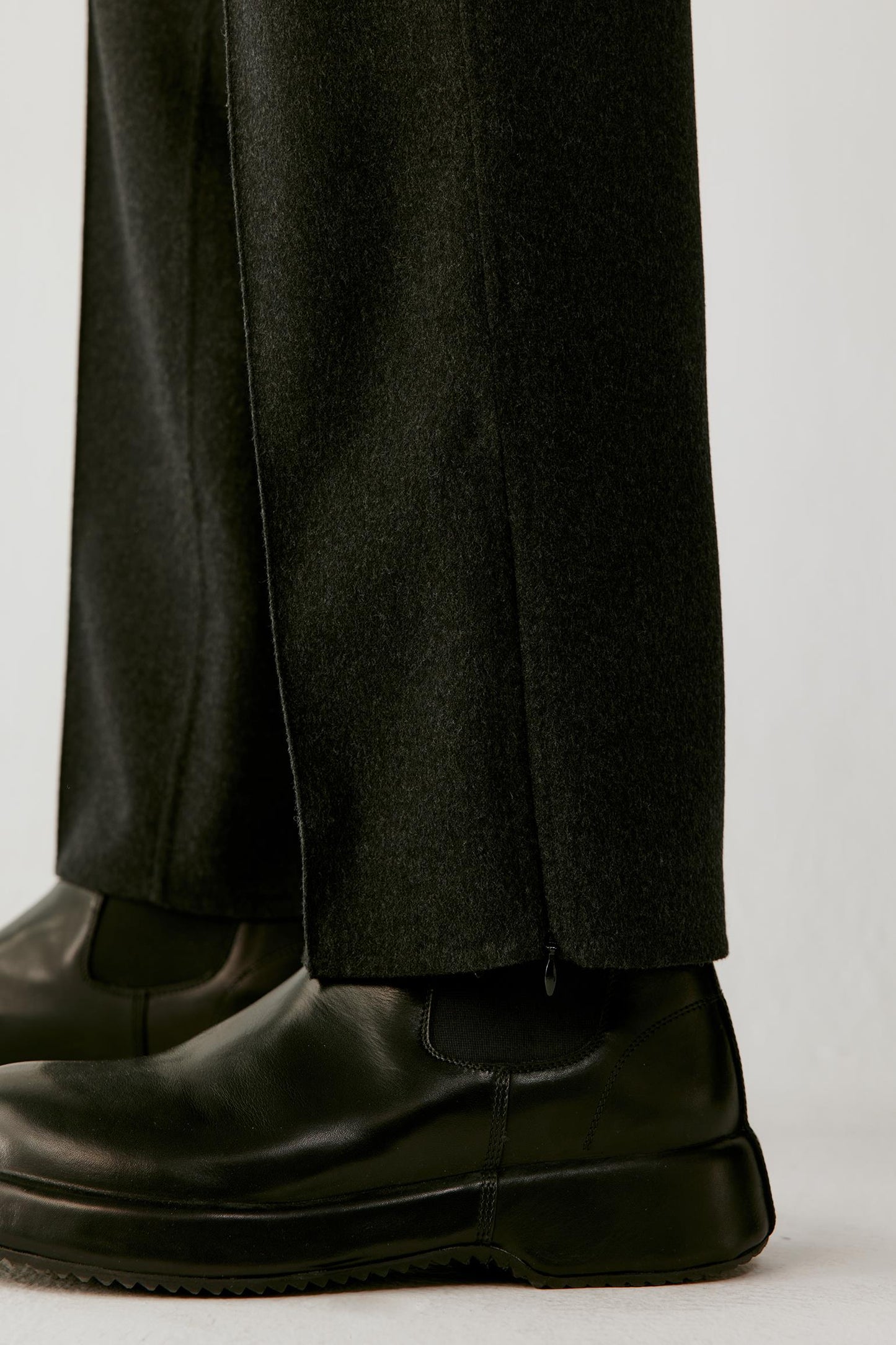 Close-up of the lower leg highlighting the side hem slit and structured double-face wool fabric.
