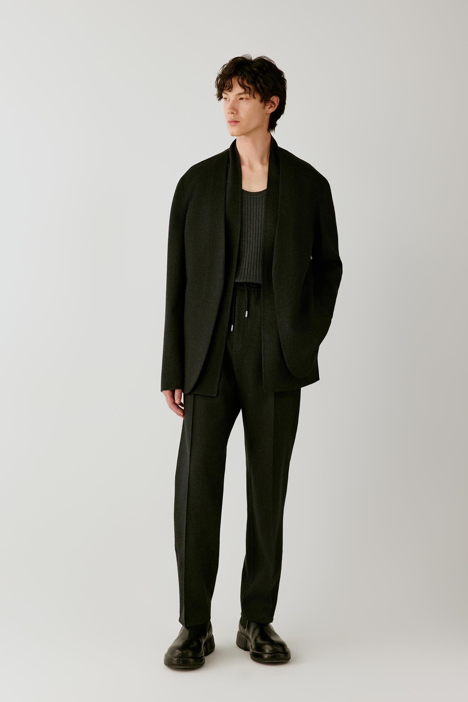 Full-length front view showing the black jacket with matching trousers, emphasizing the dropped shoulders and clean construction.