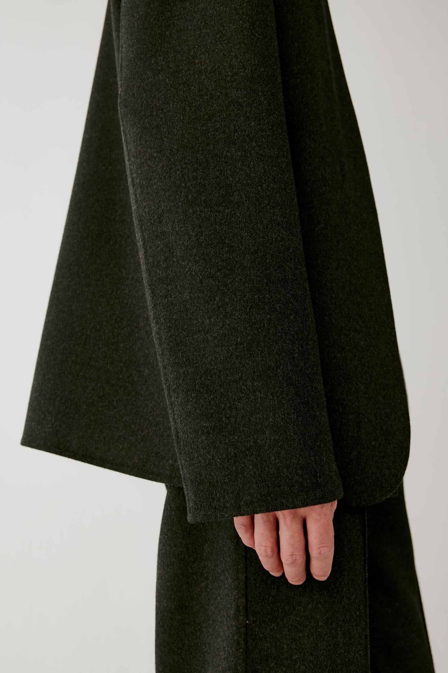 Close-up of the sleeve and cuff, showing the clean finish and smooth surface of the black wool.