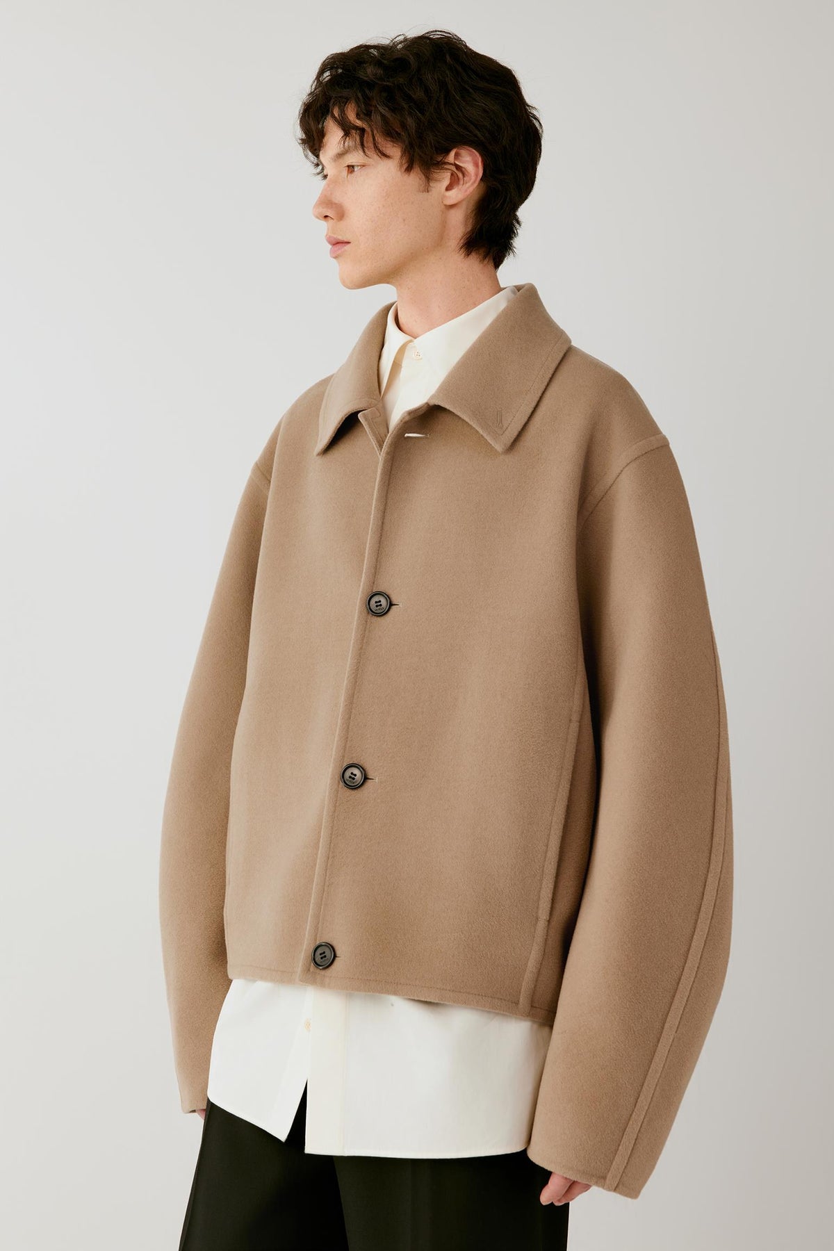 Side view highlighting the pointed collar, dropped shoulder and clean lines of the double-face wool coat.
