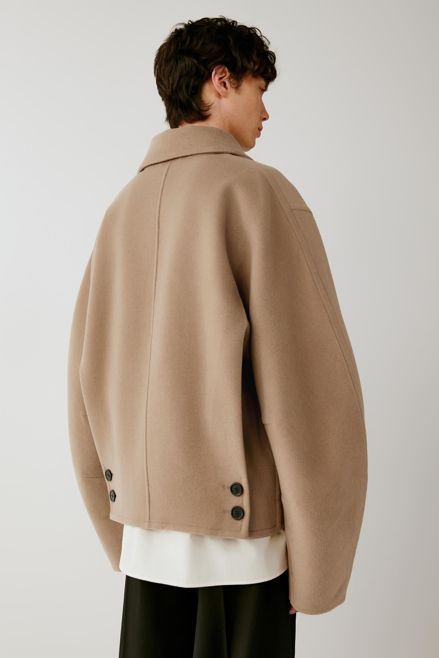 Three-quarter back view showing the relaxed back construction and camel melange surface of the double-face wool.