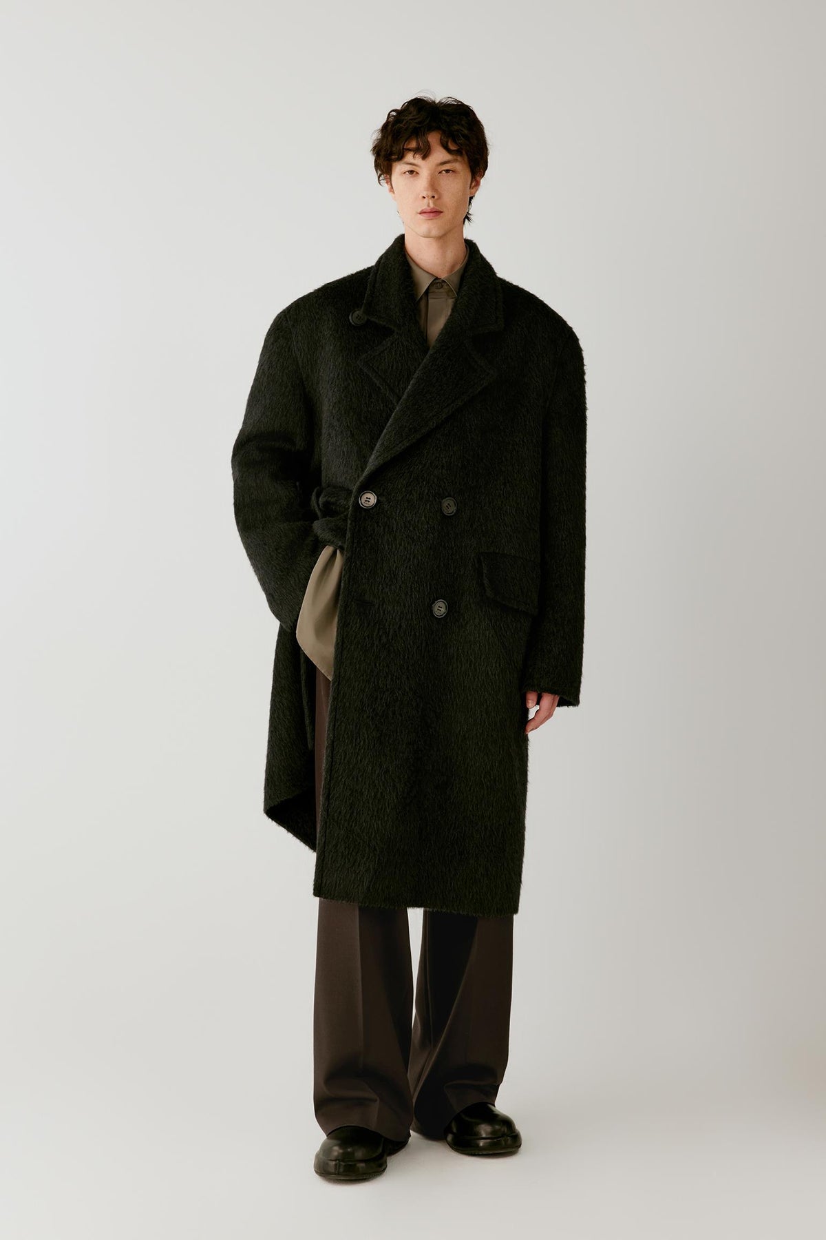Front view of a man wearing a charcoal grey camel and mohair coat, showing the long double-breasted silhouette, wide notched lapels and textured surface.