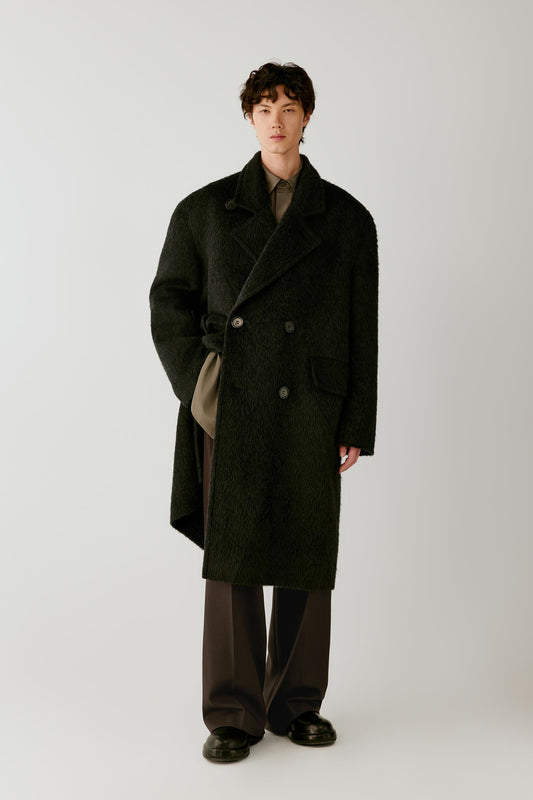 Front view of a man wearing a charcoal grey camel and mohair coat, showing the long double-breasted silhouette, wide notched lapels and textured surface.