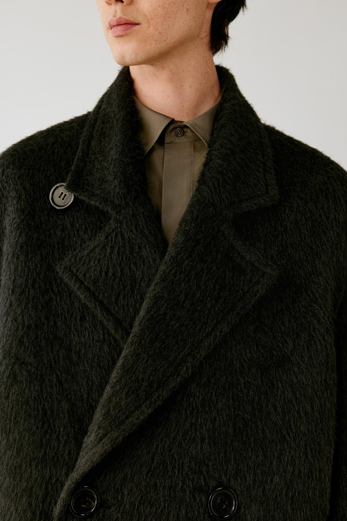 Close-up highlighting the wide notched lapels, double-breasted button fastening and furry texture of the charcoal grey camel and mohair coat.