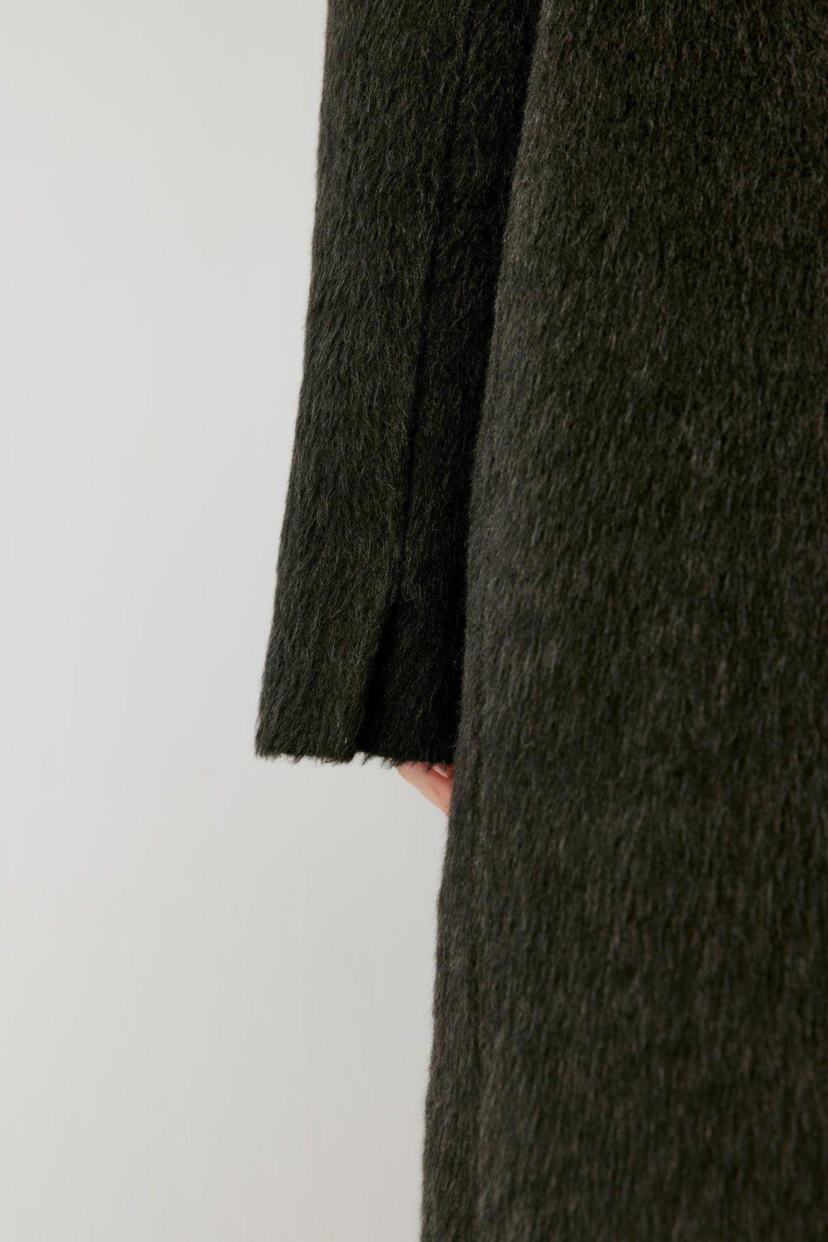 Close-up showing the richly textured surface and clean edge of the charcoal grey camel and mohair coat.
