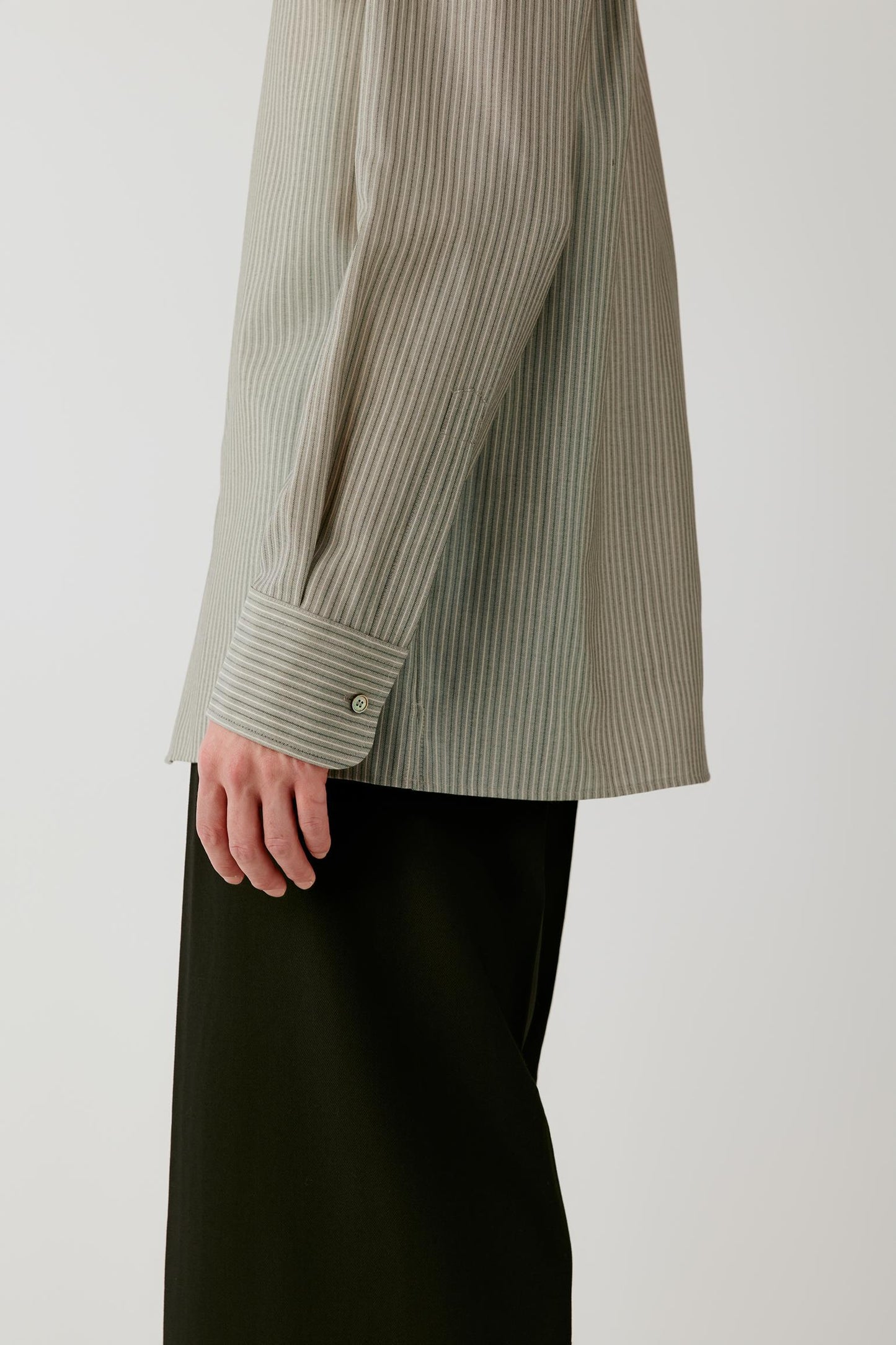 Close-up of the long sleeve and buttoned cuff, showing the fine striped pattern and crisp surface of the wool and silk fabric.