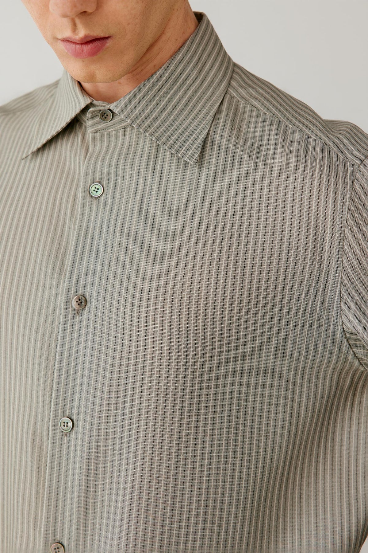 Close-up of the shirt highlighting the pointed collar, button-front fastening and fine grey vertical stripe pattern.