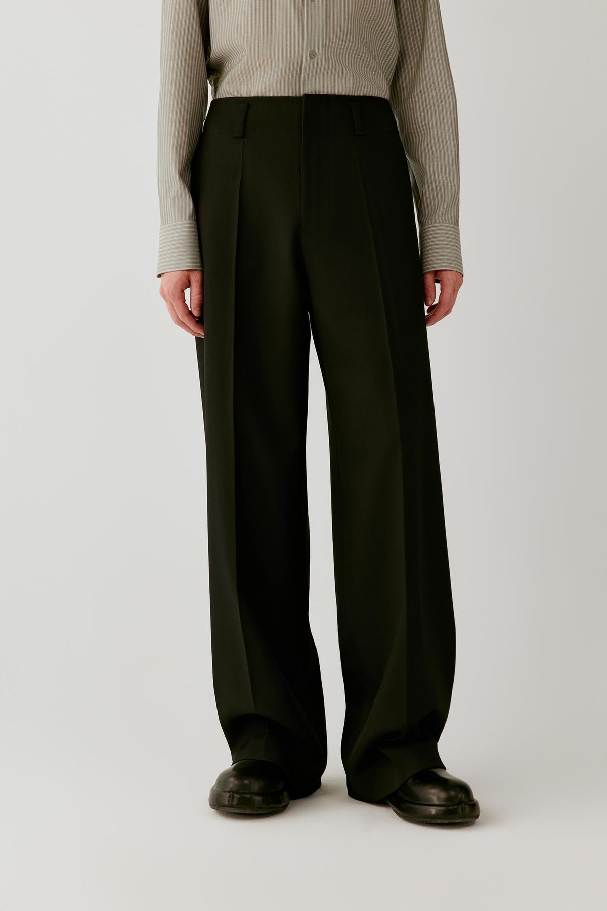 Front view focused on the trousers, emphasizing the wide-leg cut, pressed creases and structured wool twill fabric.
