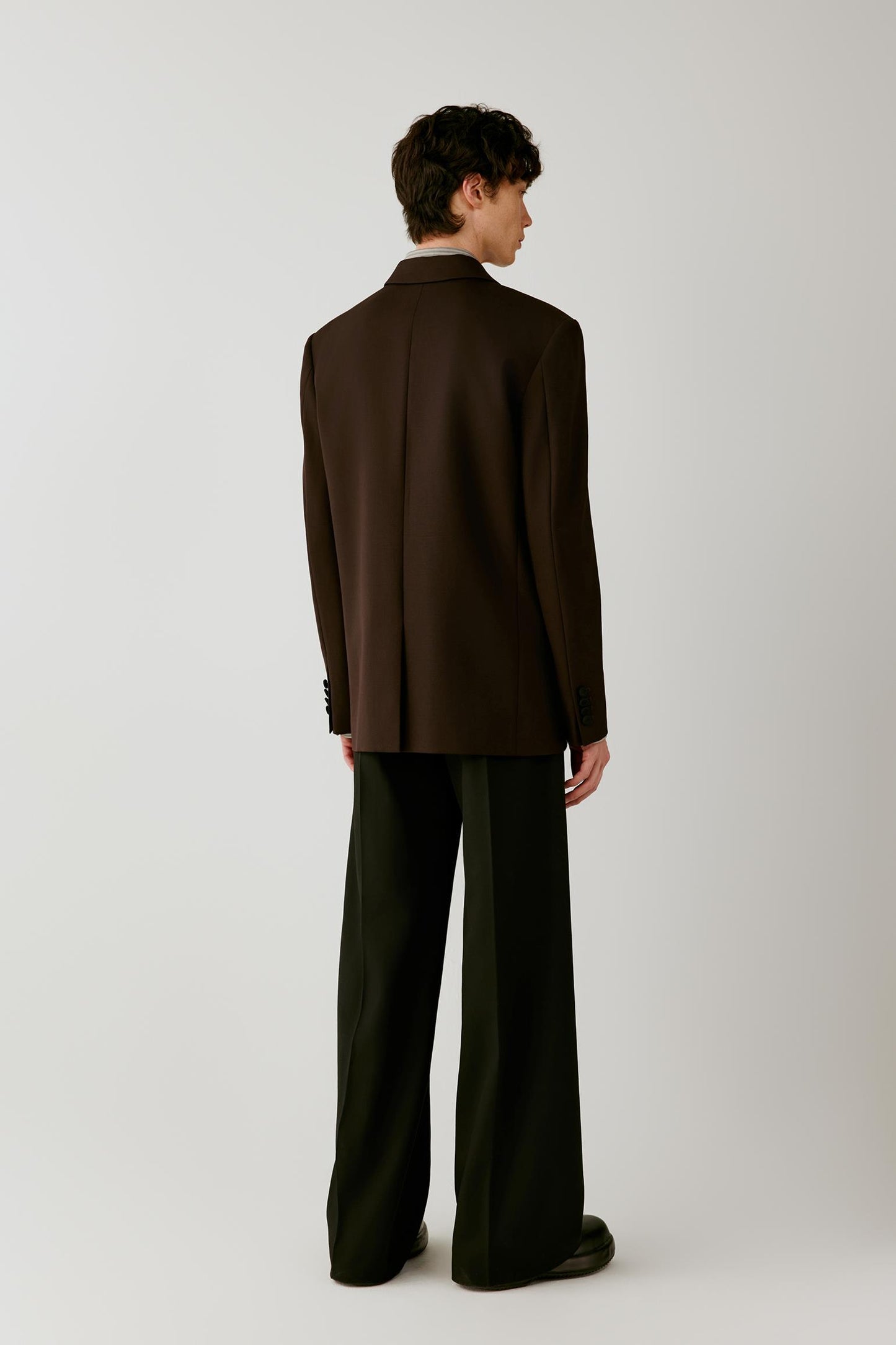 Full-length back view highlighting the clean back construction, structured shoulders and elongated silhouette.