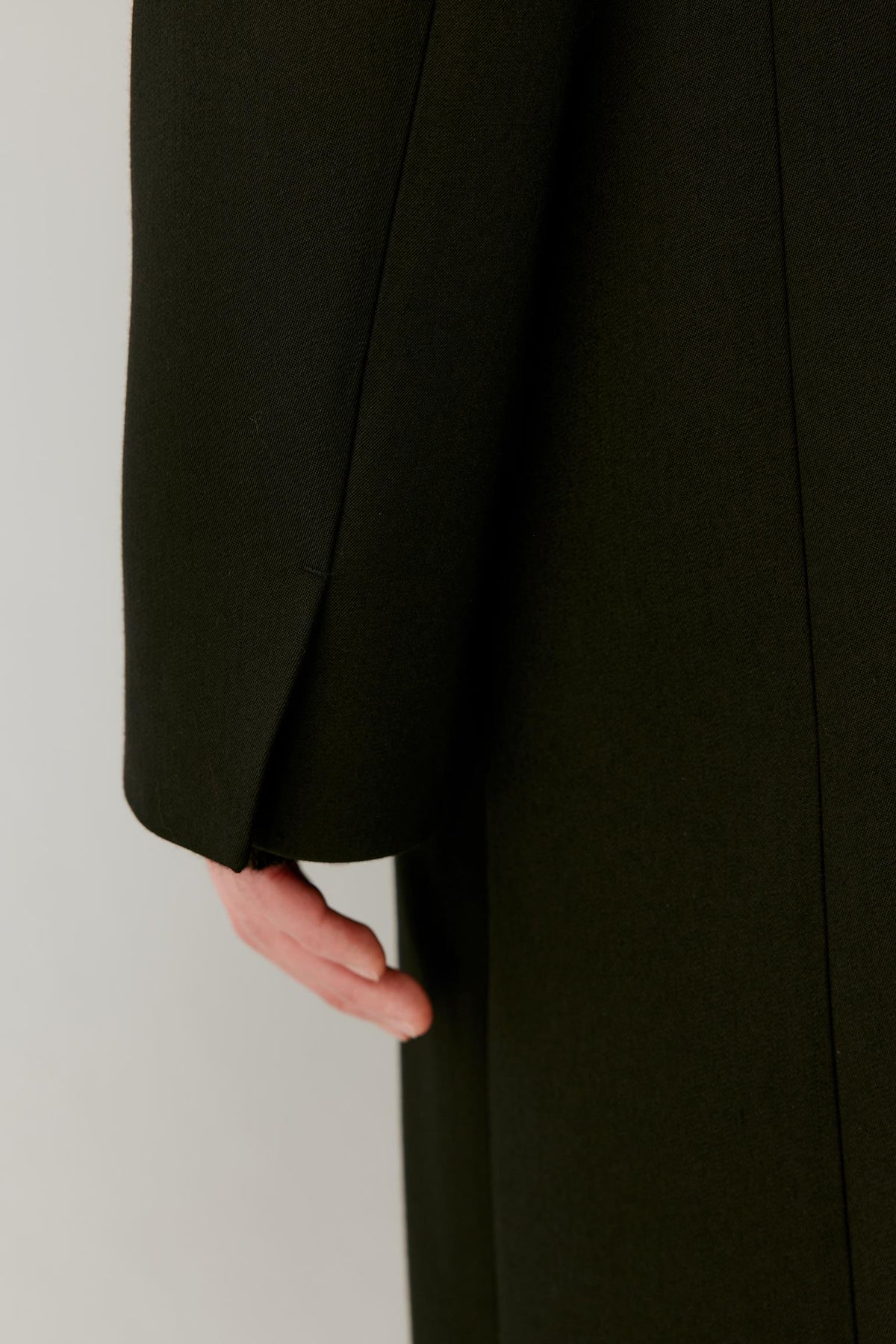 Close-up showing the long sleeve, clean cuff and dense black double-face wool surface.