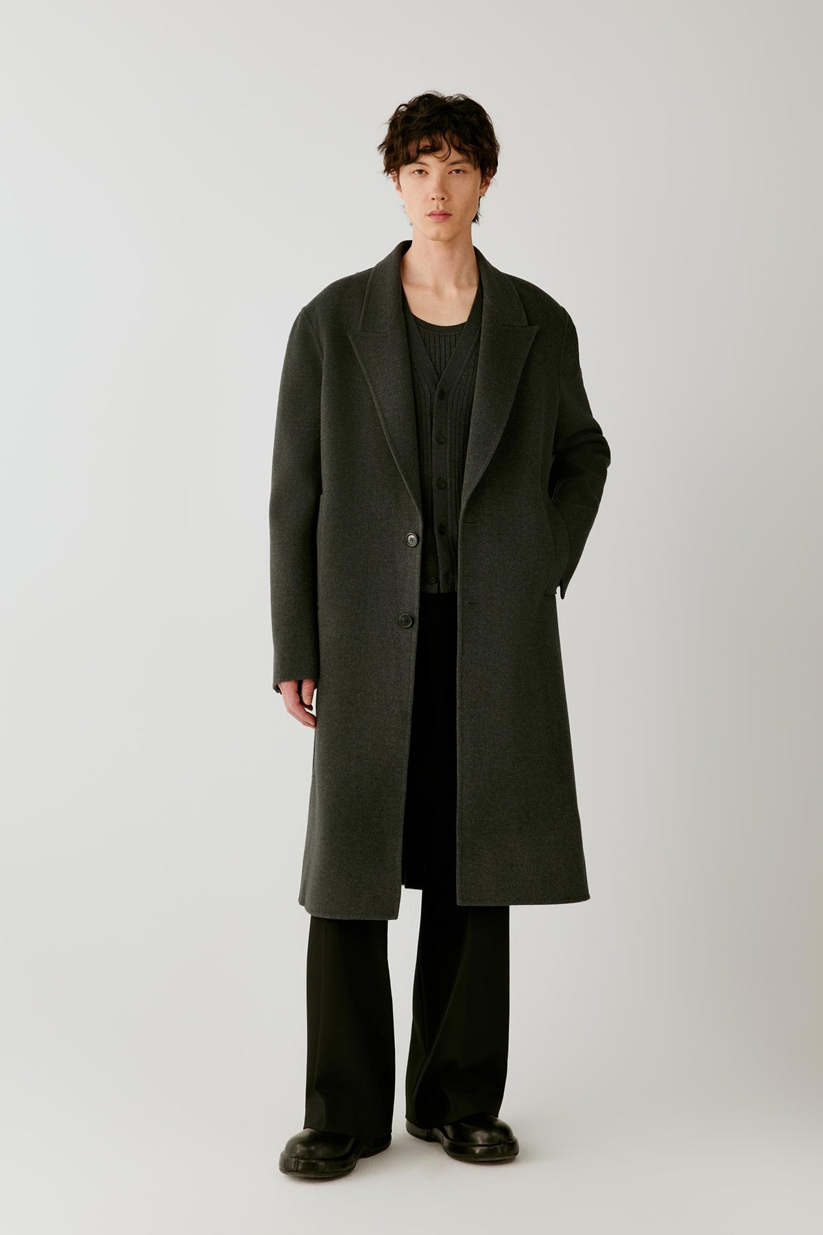 Front view of a man wearing a dark grey melange double-face wool coat, showing the long straight silhouette and notched lapels.