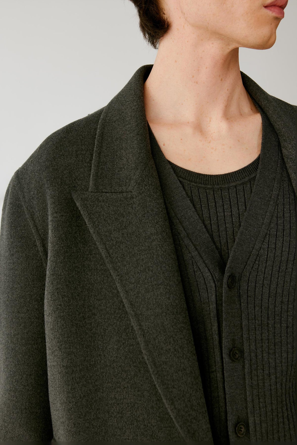 Close-up highlighting the notched lapels and softly mottled texture of the dark grey melange wool.