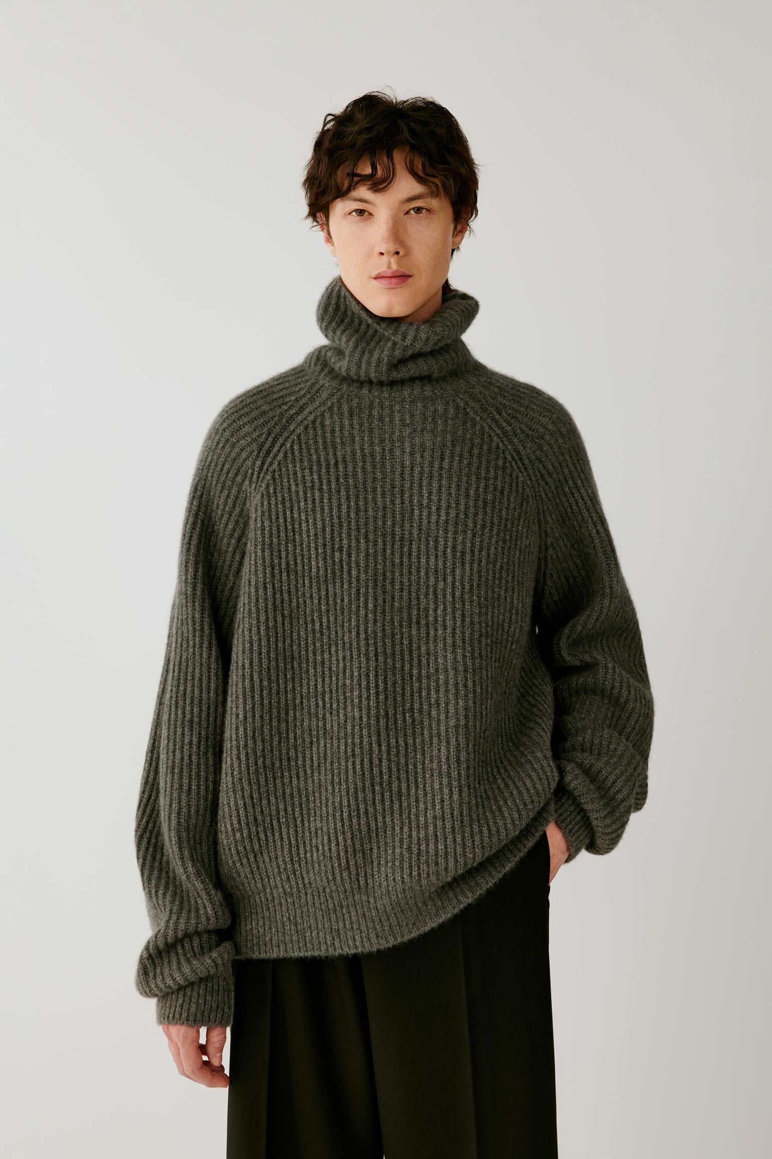 Front view of a man wearing a smoky grey cashmere and silk pullover, highlighting the oversized silhouette, folded turtleneck and ribbed knit.