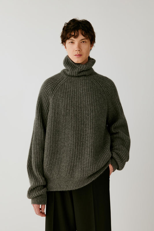 Front view of a man wearing a smoky grey cashmere and silk pullover, highlighting the oversized silhouette, folded turtleneck and ribbed knit.