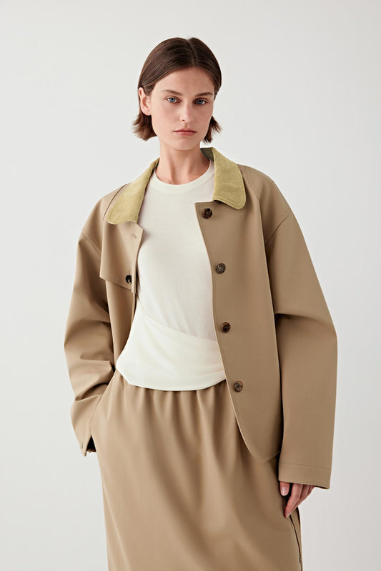 Mid-length front view with the coat open, highlighting the fluid drape, clean lines and layered silhouette over a light top