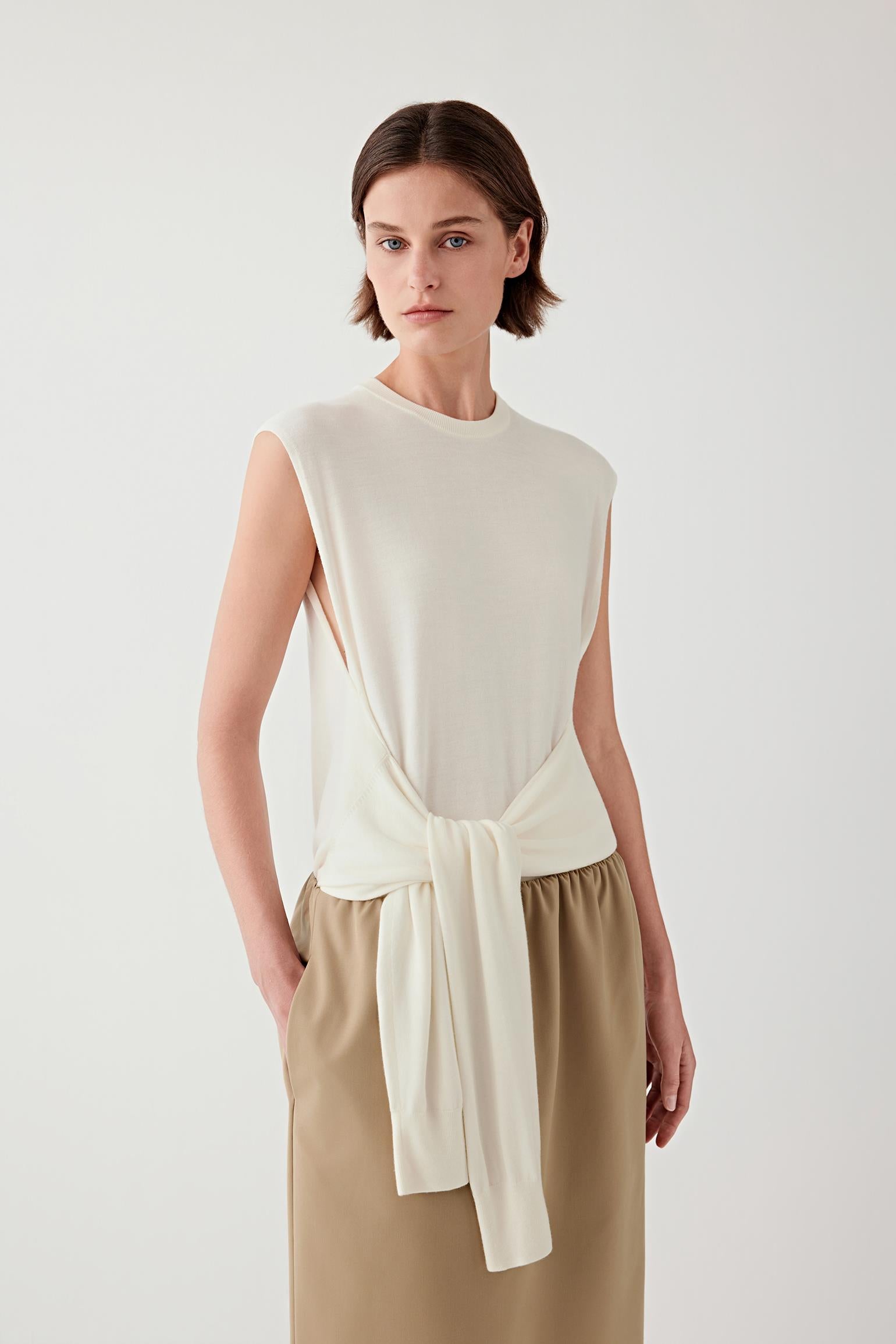 Woman wearing a cream sleeveless wool pullover with a matching skirt, front view.