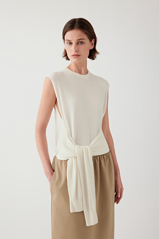 Woman wearing a cream sleeveless wool pullover with a matching skirt, front view.