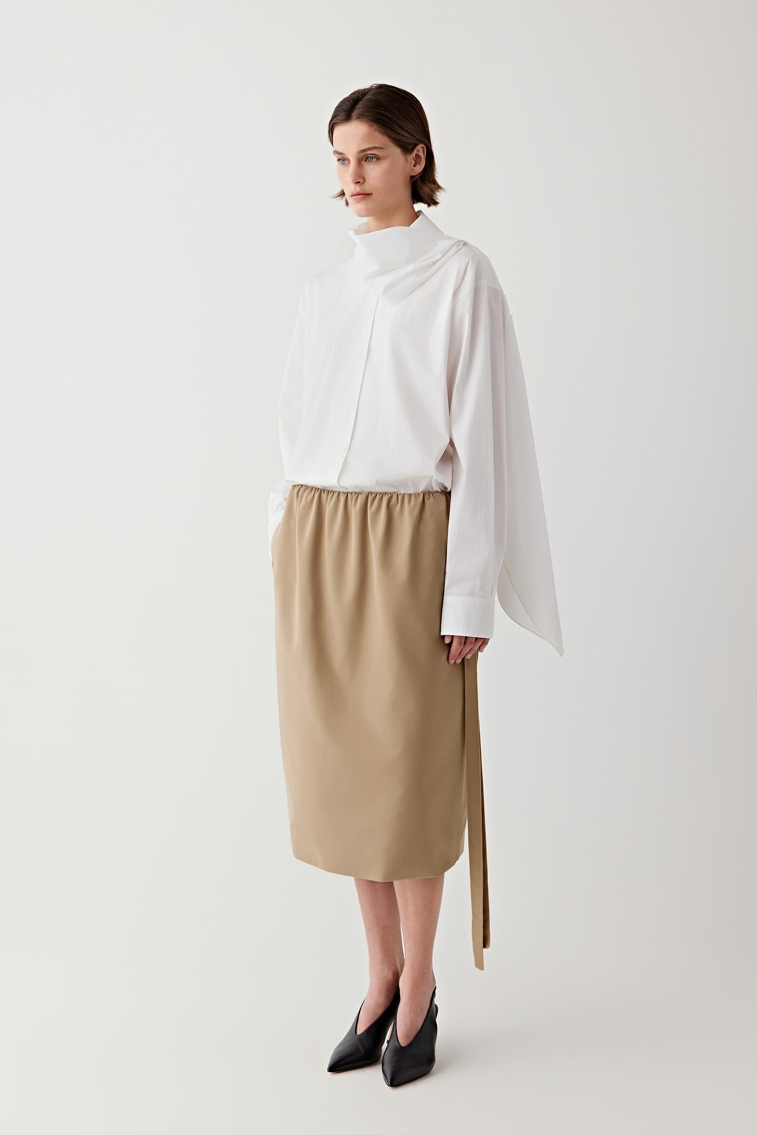 Woman wearing a white blouse and beige skirt on a white background